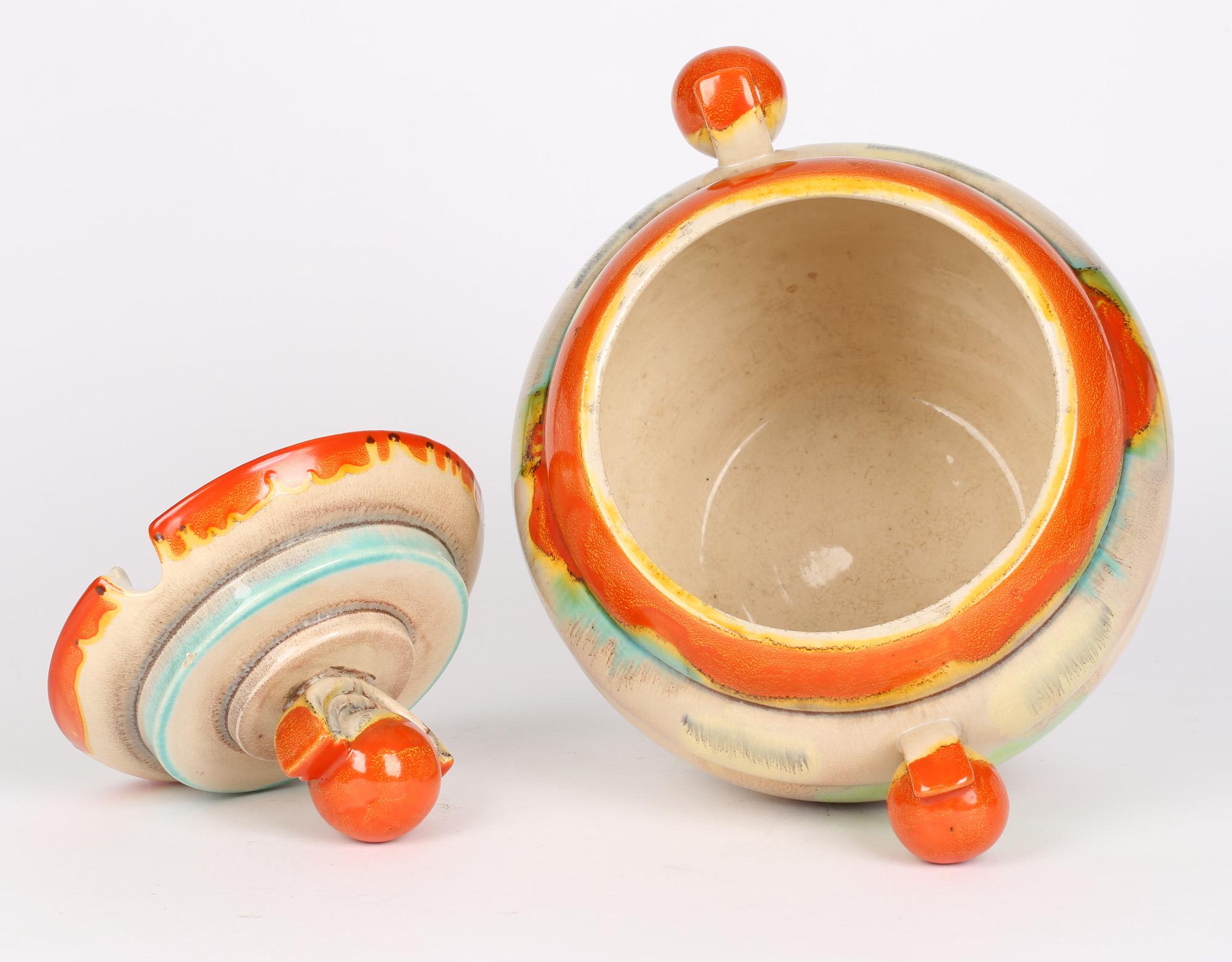 A very stylish Art Deco German pottery lidded punch pot or soup tureen decorated in brightly colored glazes attributed to Dumler & Breiden and dating from around 1930. The large rounded pot stands on a narrow rounded foot and has stylized ball