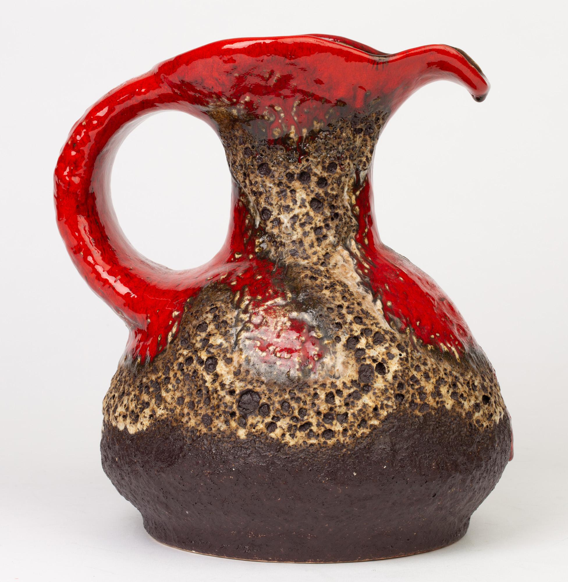 A stunning and large German midcentury art pottery jug decorated in lava glazes by Dümler & Breiden and dating from circa 1950-1960. The large heavily made jug has a wide squat bulbous shaped body with narrow funnel shaped neck and large opening