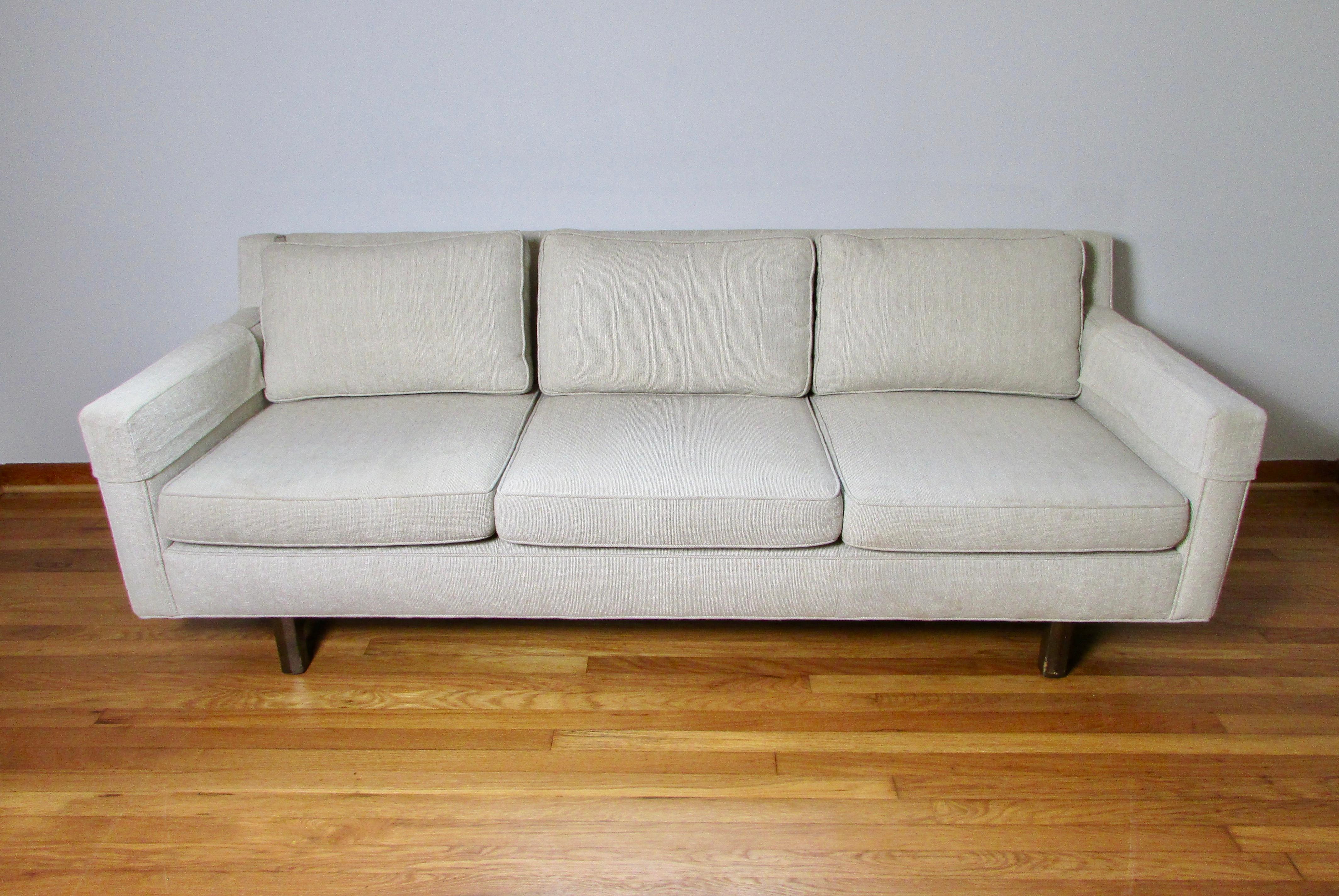 Mid-Century three seat sofa in a sandy beige and white woven upholstery similar to a boucle. Three down-filled back cushions and three foam seat cushions make this a comfortable and good looking sofa. Acquired from a  interior designer's mid century