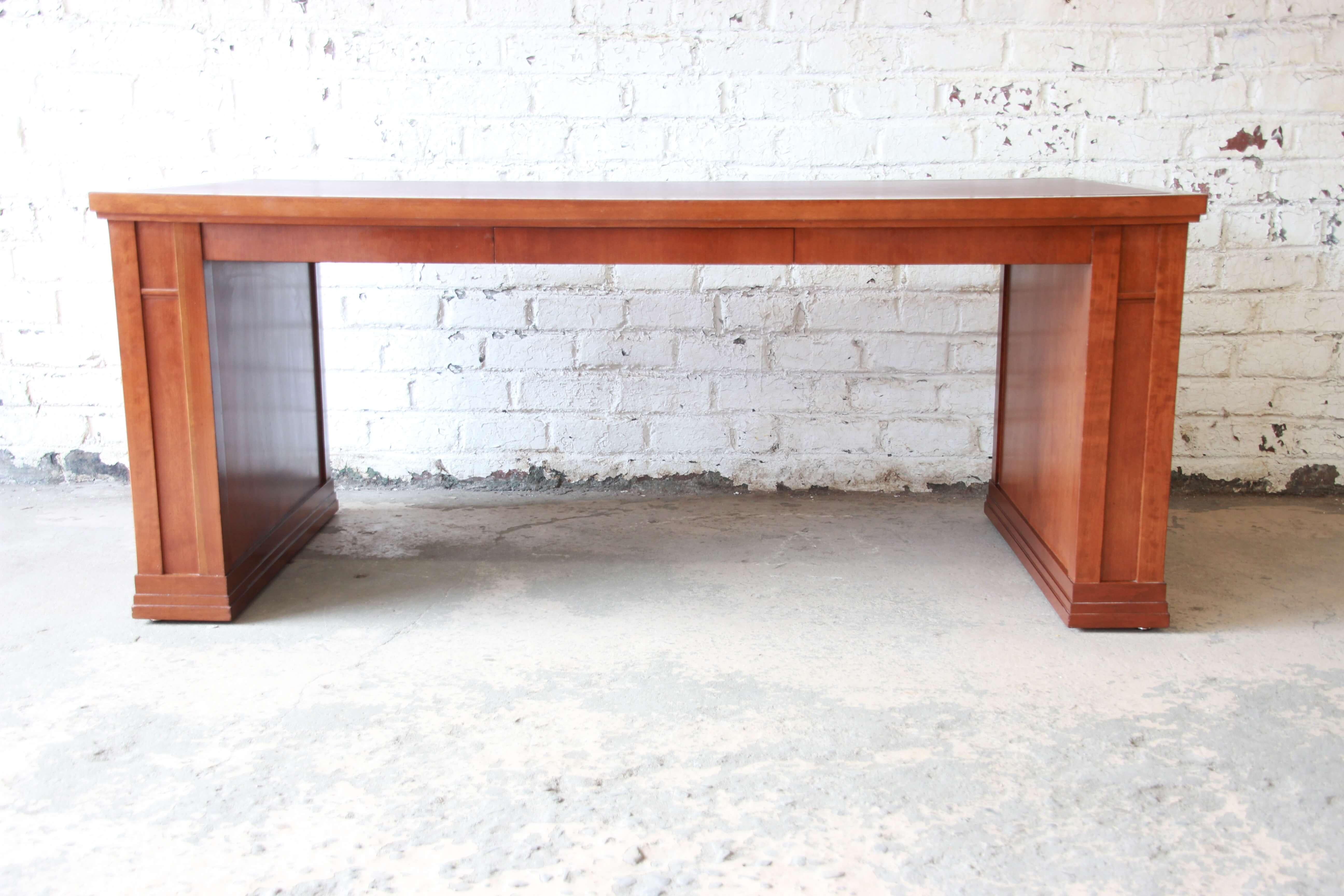 Offering a very nice and rare Dunbar cherry leather top desk or library table. The desk has a nice Craftsman/Frank Lloyd Wright style in a simple and elegant design. The top has a burgundy leather top with a substantial writing surface. The centre
