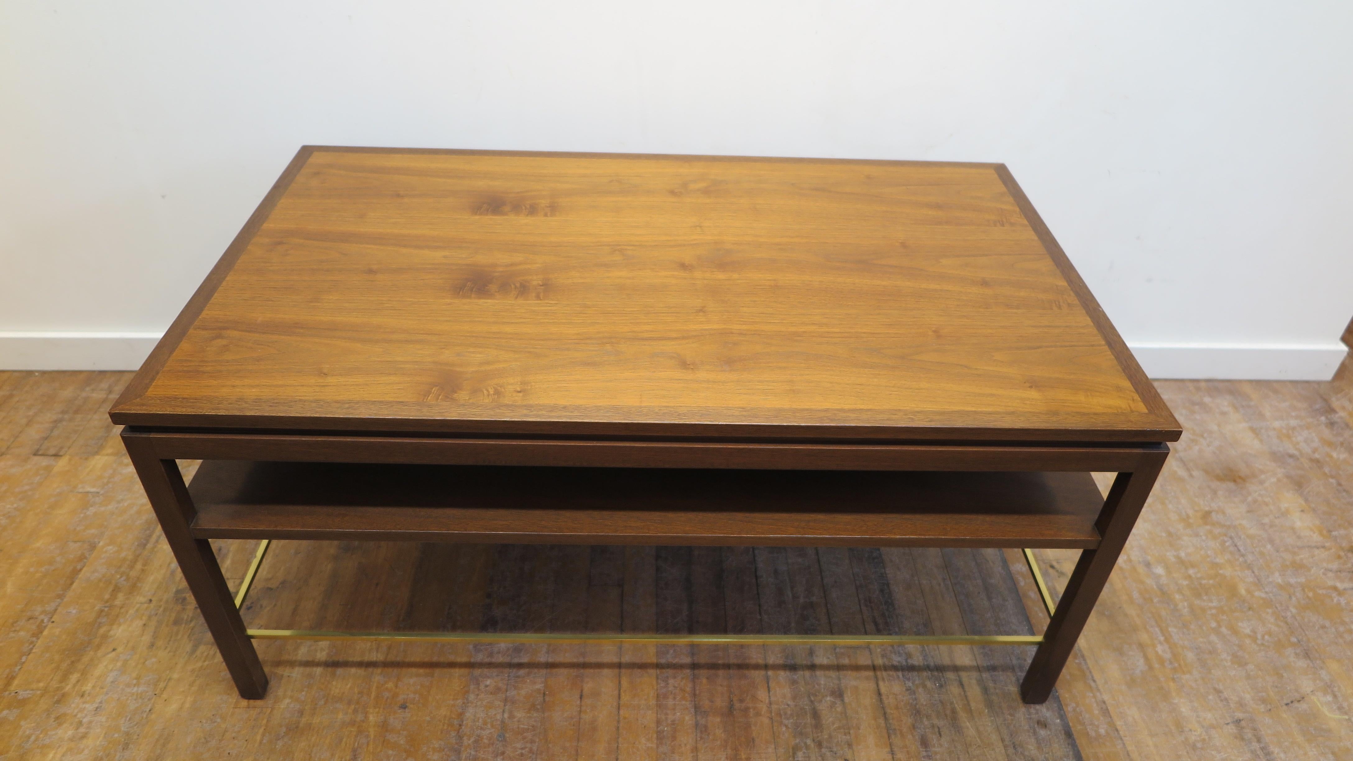 Dunbar cocktail table designed by Edward Wormley for Dunbar. Coffee table in two tone walnut with lower shelf and brass stretcher. Very good original condition. 
Very light wear to the top.