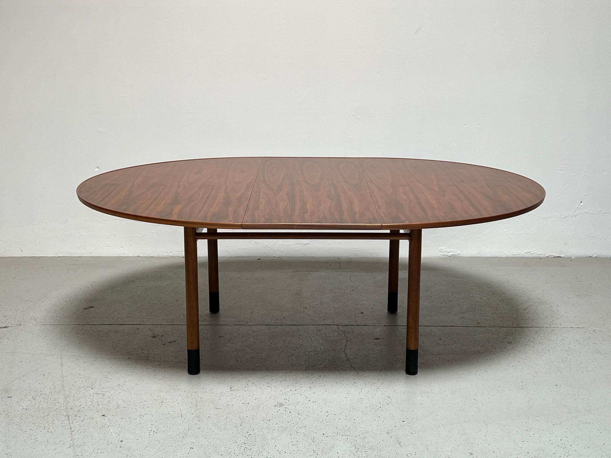 A beautifully grained walnut dining table with leather wrapped feet. Designed by Edward Wormley for Dunbar. Table measures 60