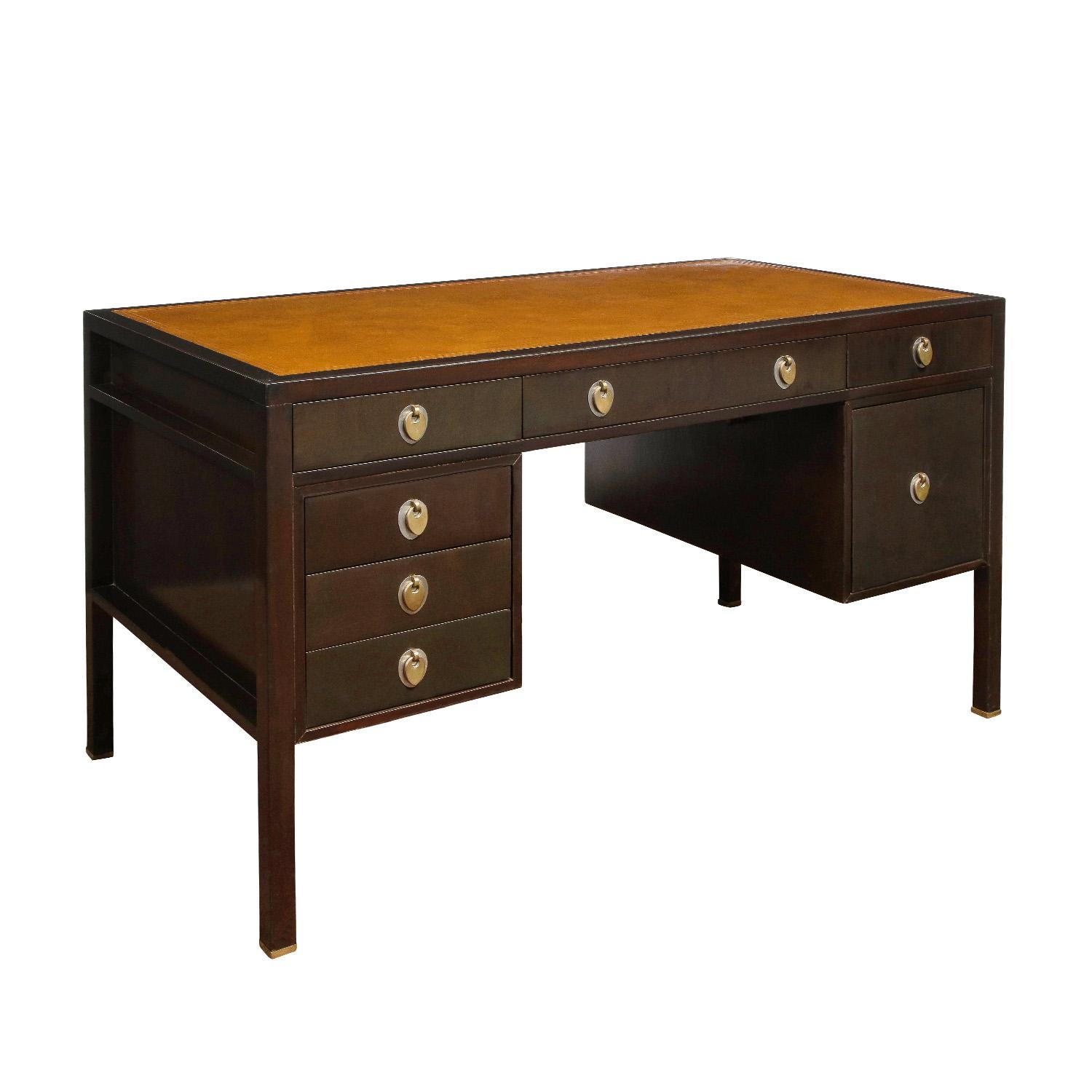 Beautifully crafted desk in dark mahogany with inset leather top and sculpted oval chrome and brass pulls as well as brass feet by Edward Wormley for Dunbar, American 1960's (signed with metal Dunbar label in drawer). The mixed metal pulls are a