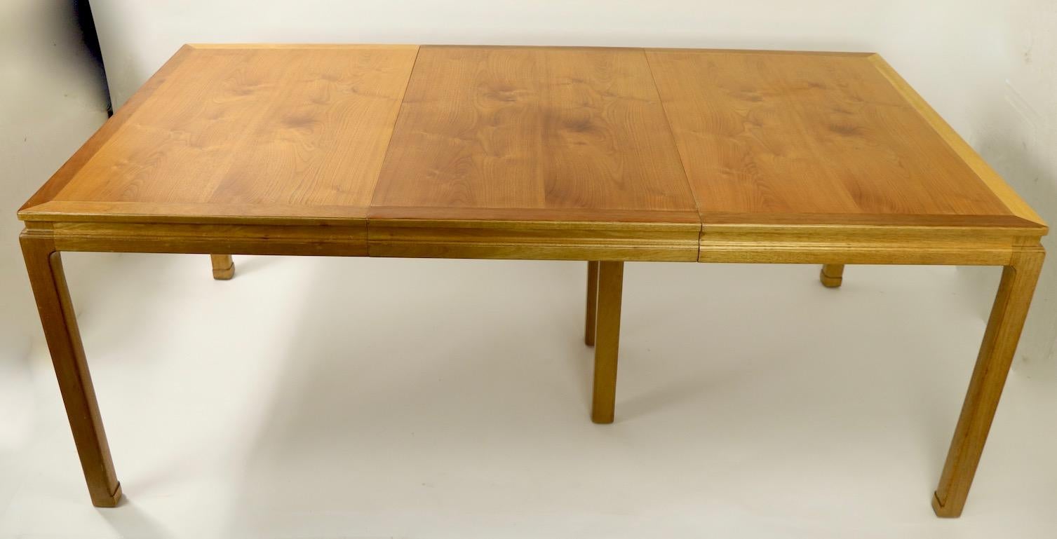 Classic Asia Modern style dining table designed by Edward Wormley for Dunbar. This example comes with one 24 in leaf, and the fold up center support leg. As expected from Dunbar, this table exhibits sophisticated design, expert craftsmanship, and