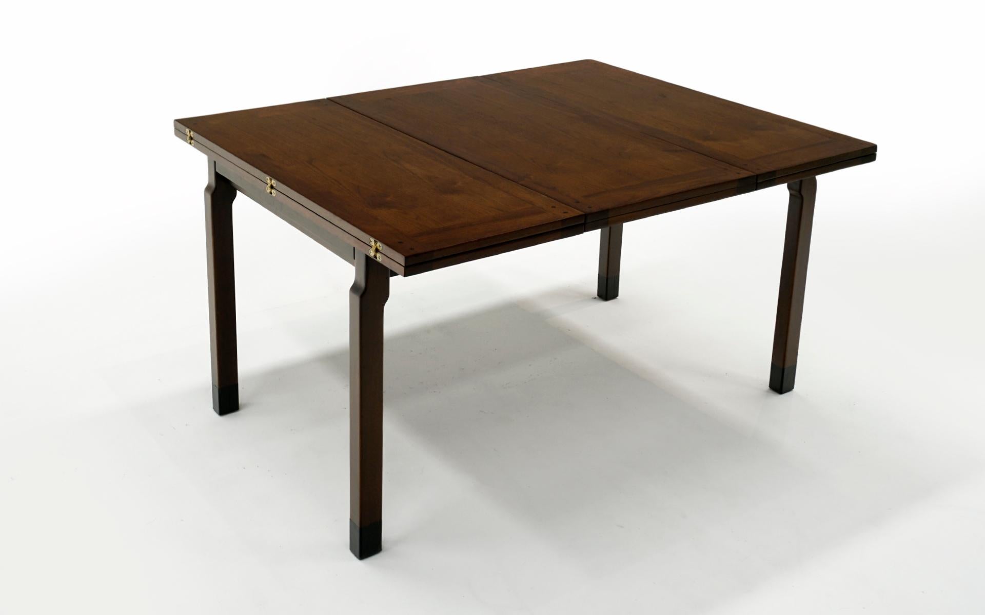 Sehr seltener, erweiterbarer Esstisch, entworfen von Edward Wormley für Dunbar, 1950er Jahre.  Nussbaumholz mit schwarzen Lederknöcheln und Messingbeschlägen.  Die Tabelle beginnt bei 54 Zoll breit und erstreckt sich auf 84 Zoll breit, wenn die