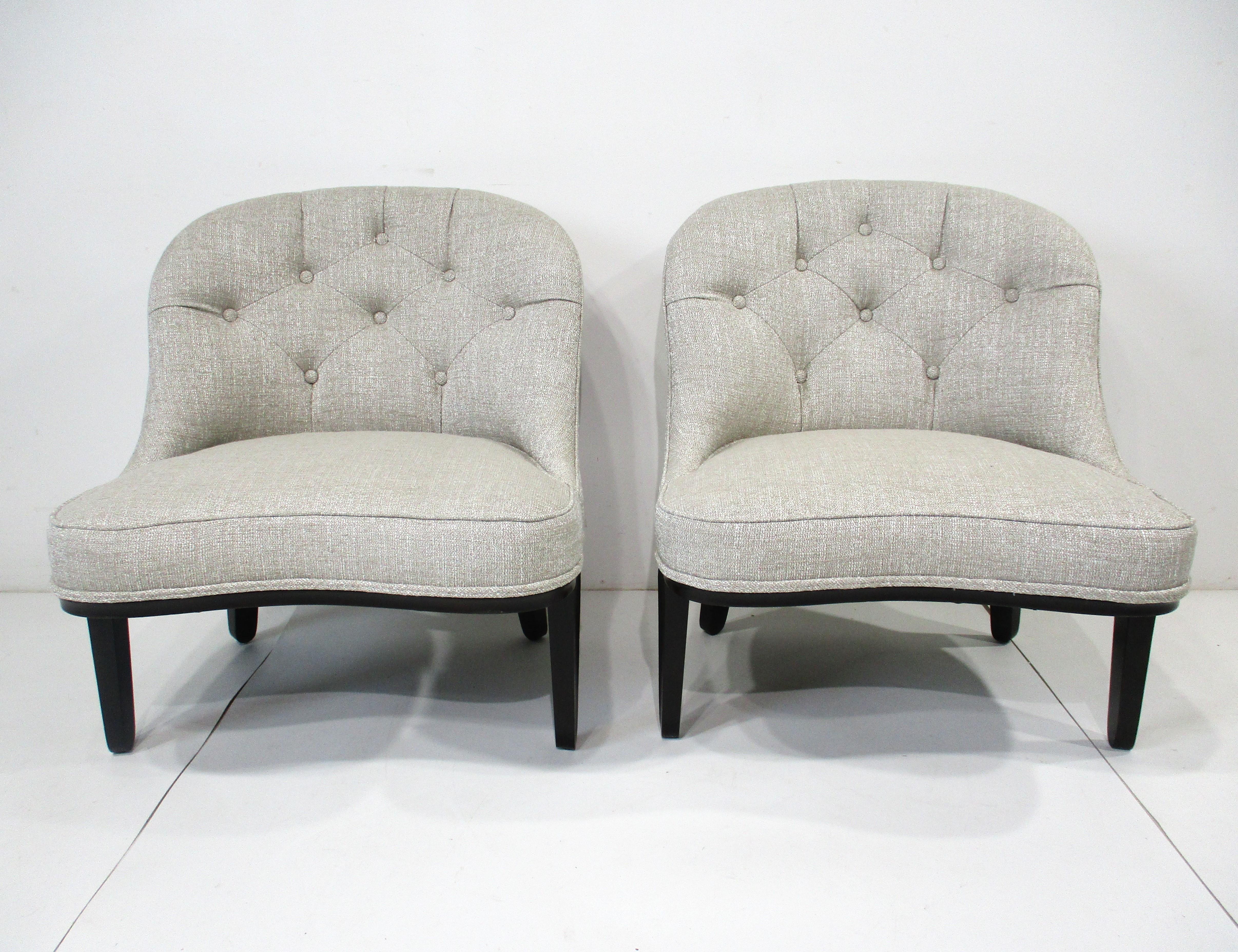 A pair of very well crafted upholstered lounge chairs with tufted backs in a light taupe and cream fabric with sculptural ebony toned mahogany legs . From the Dunbar Furniture Company known during the period as the top manufacturer using handcrafted