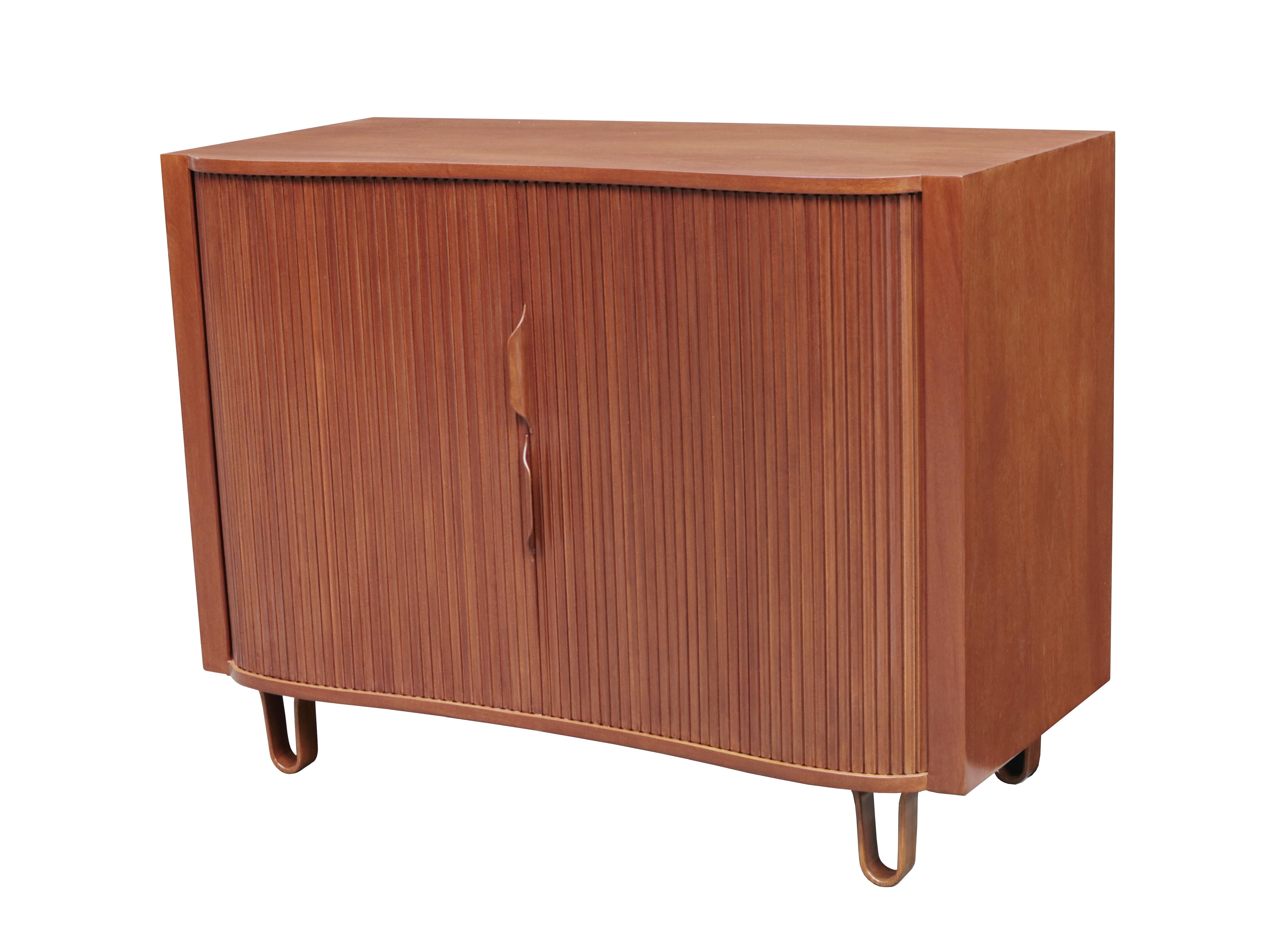 Mahogany with curved tambour doors with sixteen interior drawers in two banks, resting on hairpin legs.