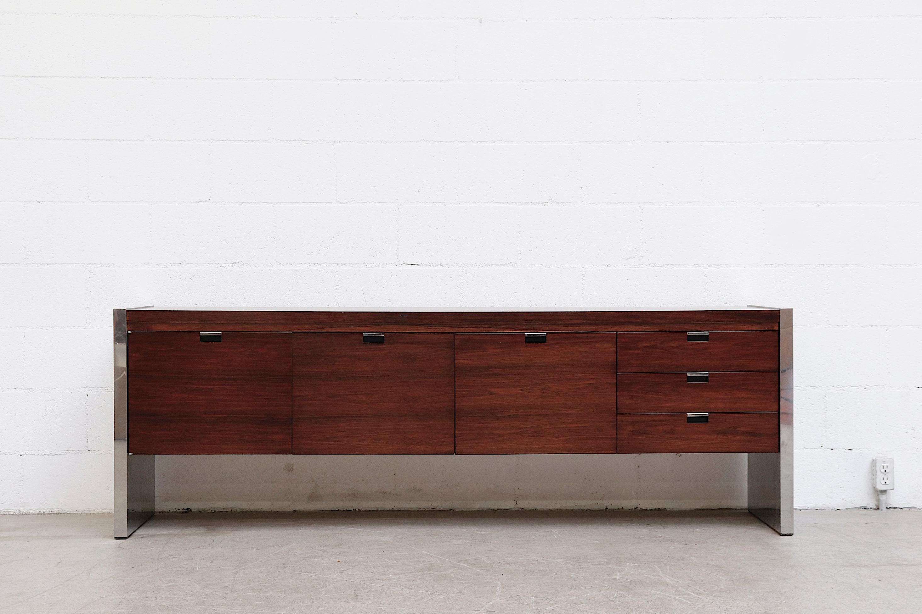 Beautiful midcentury rosewood and chrome credenza by Karl Sprunger for Dunbar. Lightly refinished with two large pull-out drawers, a single storage cabinet and three side stacked drawers with chrome sides and matching handles. In original condition
