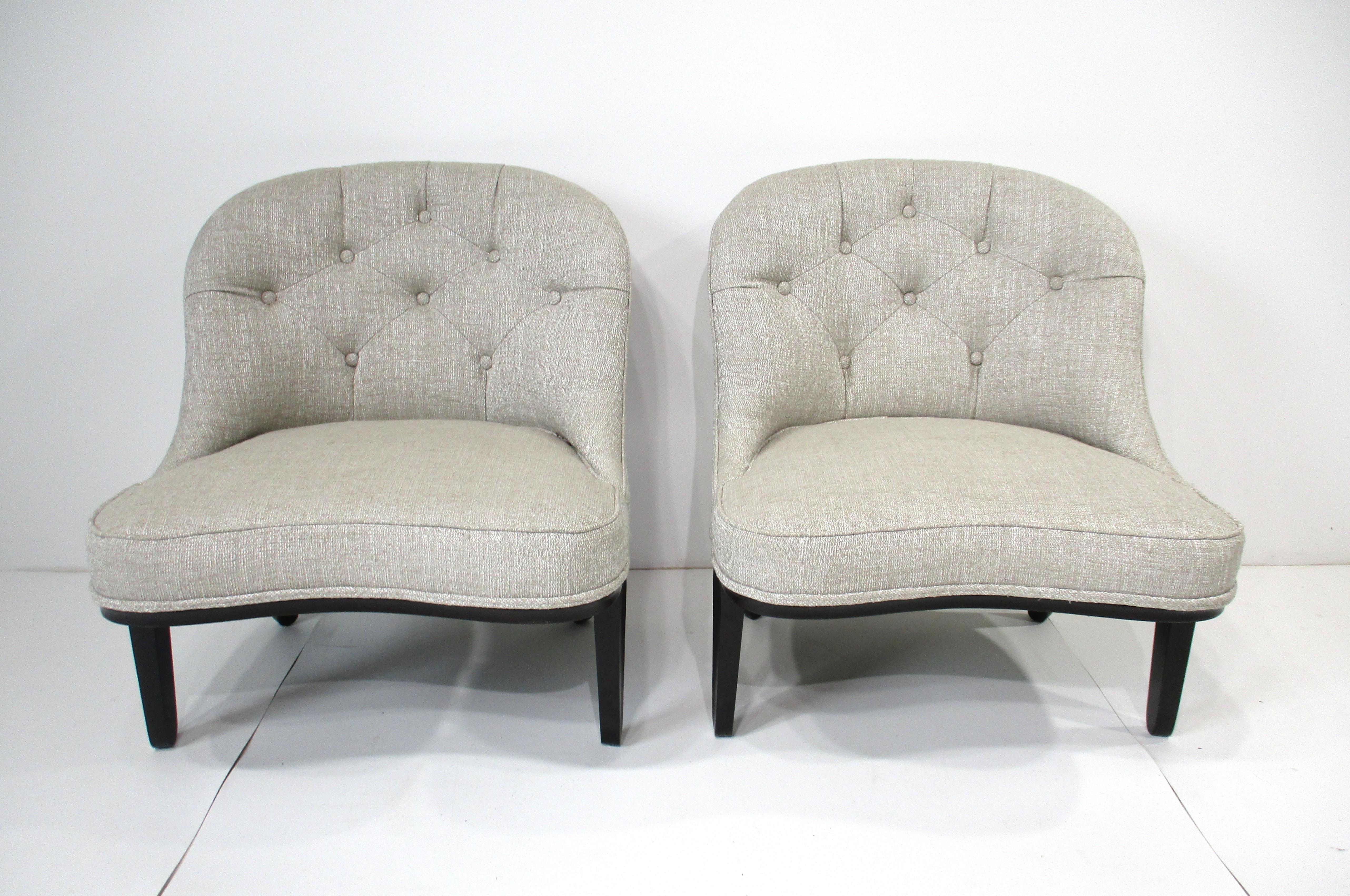 Un par de sofisticadas y muy bien elaboradas sillas slipper con respaldos acolchados tapizados en una tela tejida de color topo claro y crema con esculturales patas de caoba en tono ébano . De la Dunbar Furniture Company, conocida en la época por