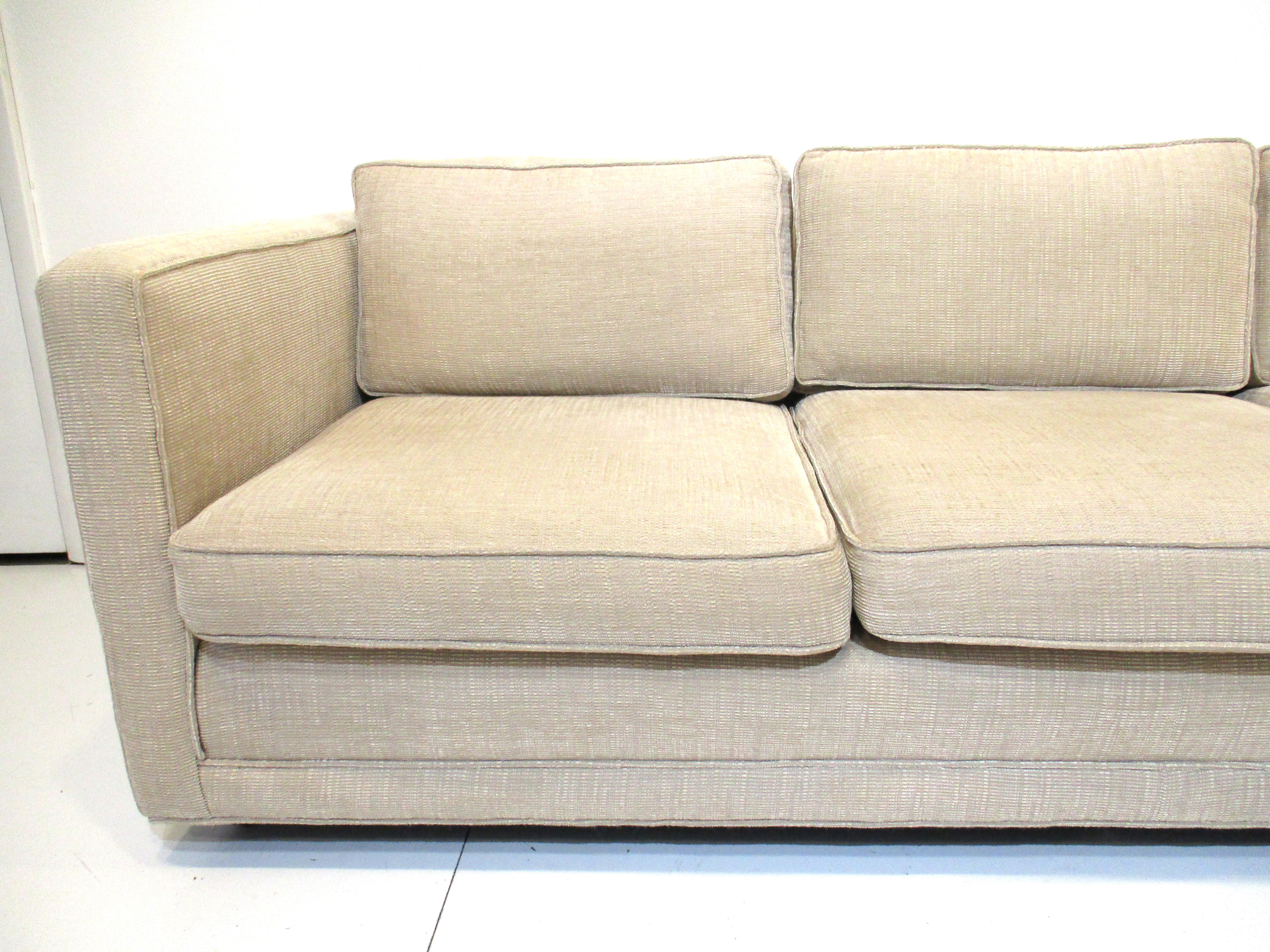 A nice comfortable loose cushion sofa in a medium sand toned fabric constructed very well as only the Dunbar furniture company would do. Sitting on wheels the piece has that minimalistic simple visual appeal that is always current and will fit with