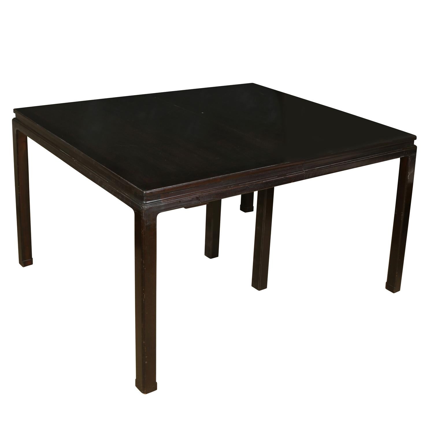 A lacquered dining table in Dunbar style with two leaves. A dark, gloss finished, Mid-Century Modern style table.