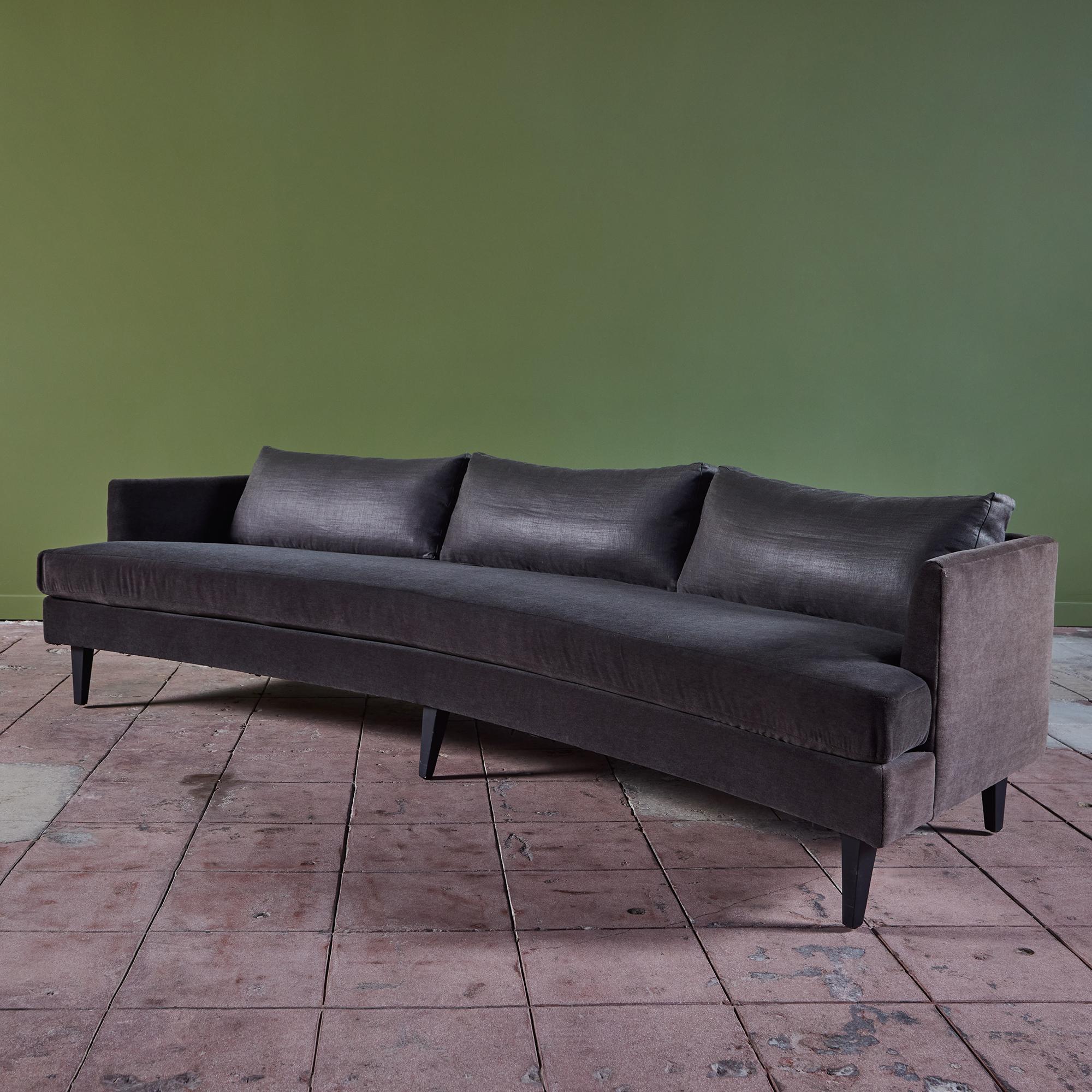 Curved sofa in the style of Dunbar. This sofa features a beautiful dark gray mohair upholstery on the frame and seat. The backrest has three pillows upholstered in a dark gray linen cotton blend, a perfect contrast to the rich mohair. The sofa sits