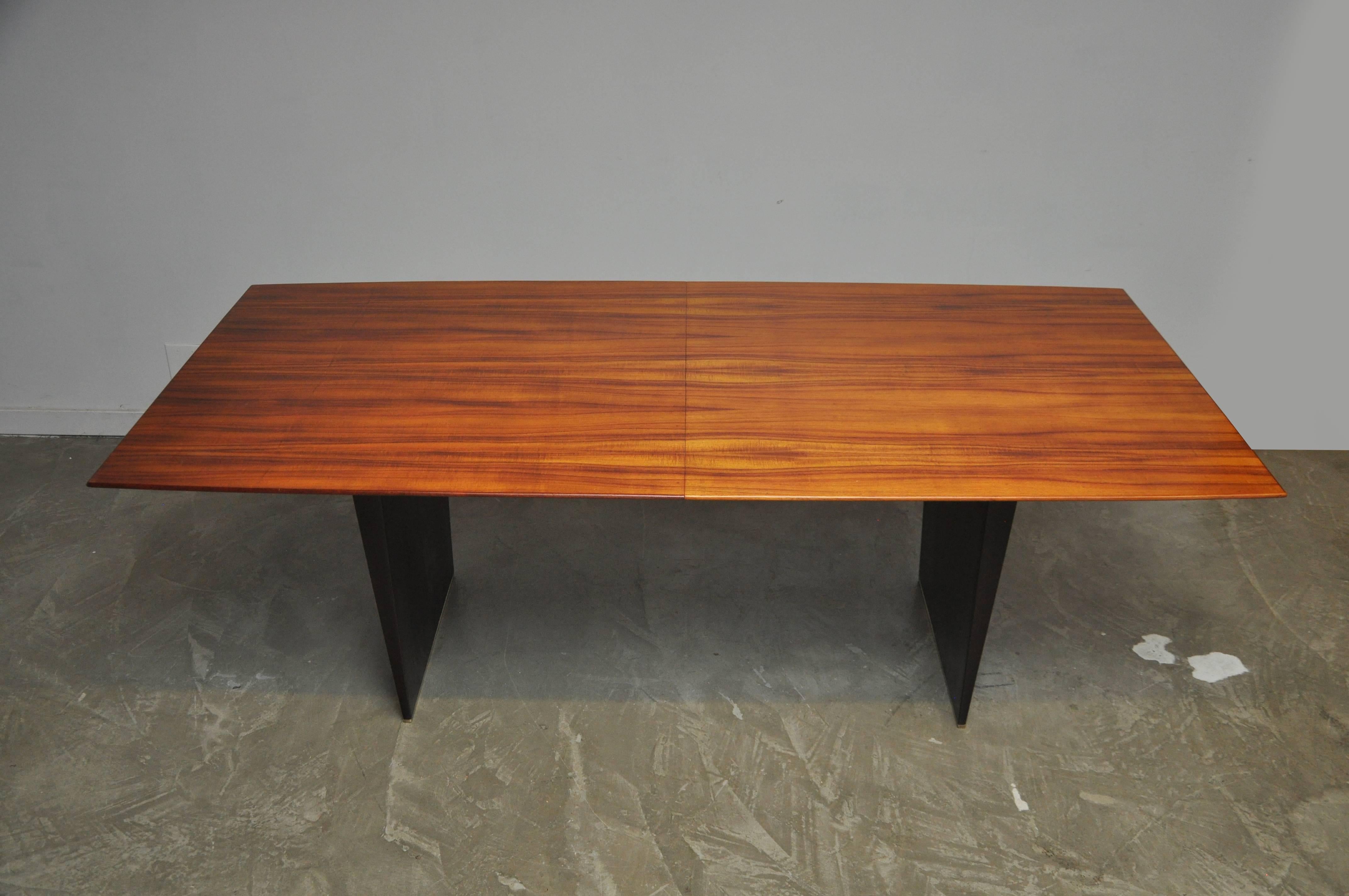 Extension dining table No. 5461 by Edward Wormley for Dunbar. Figured Tawi top on mahogany slab bases with brass shoes. 84