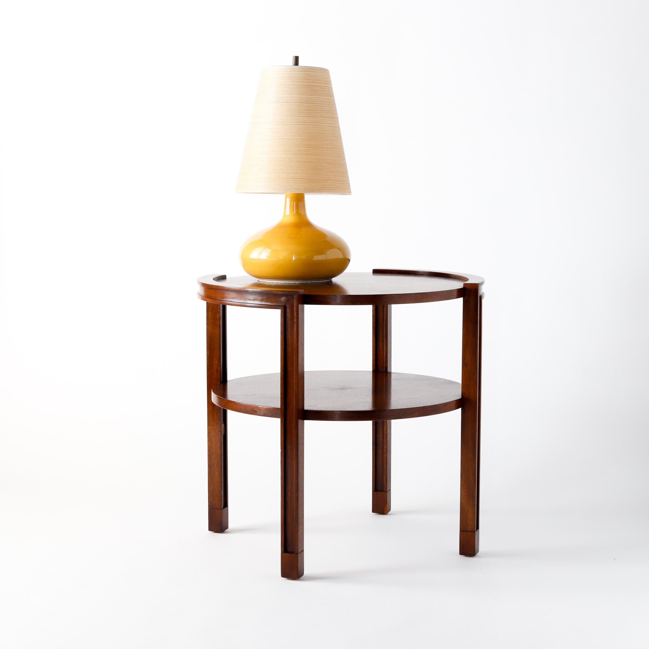 Two-tier round walnut side table by Edward Wormley for Dunbar, with a shelf beneath the main table surface. Each side has a molded rail turning into the legs. Label and metal tag on the underside, circa 1960. 

Measures: 22 1/8 inches high, 23 3/8