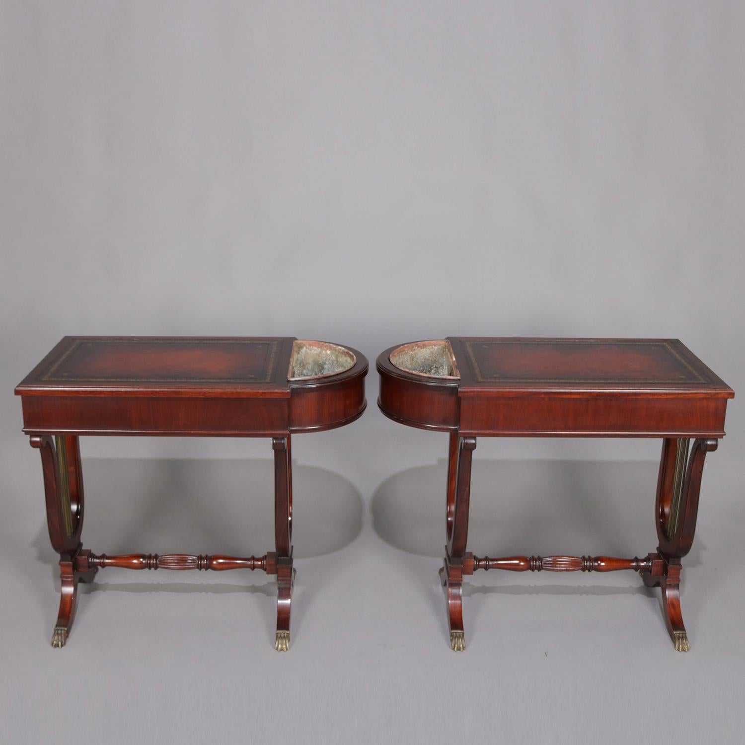 Pair of Duncan Phyfe School side stands feature mahogany construction with leather top case having lined demilune side planters and raised on lyre form legs with turned stretcher and cast bronze feet, circa 1930.

Measures: 26