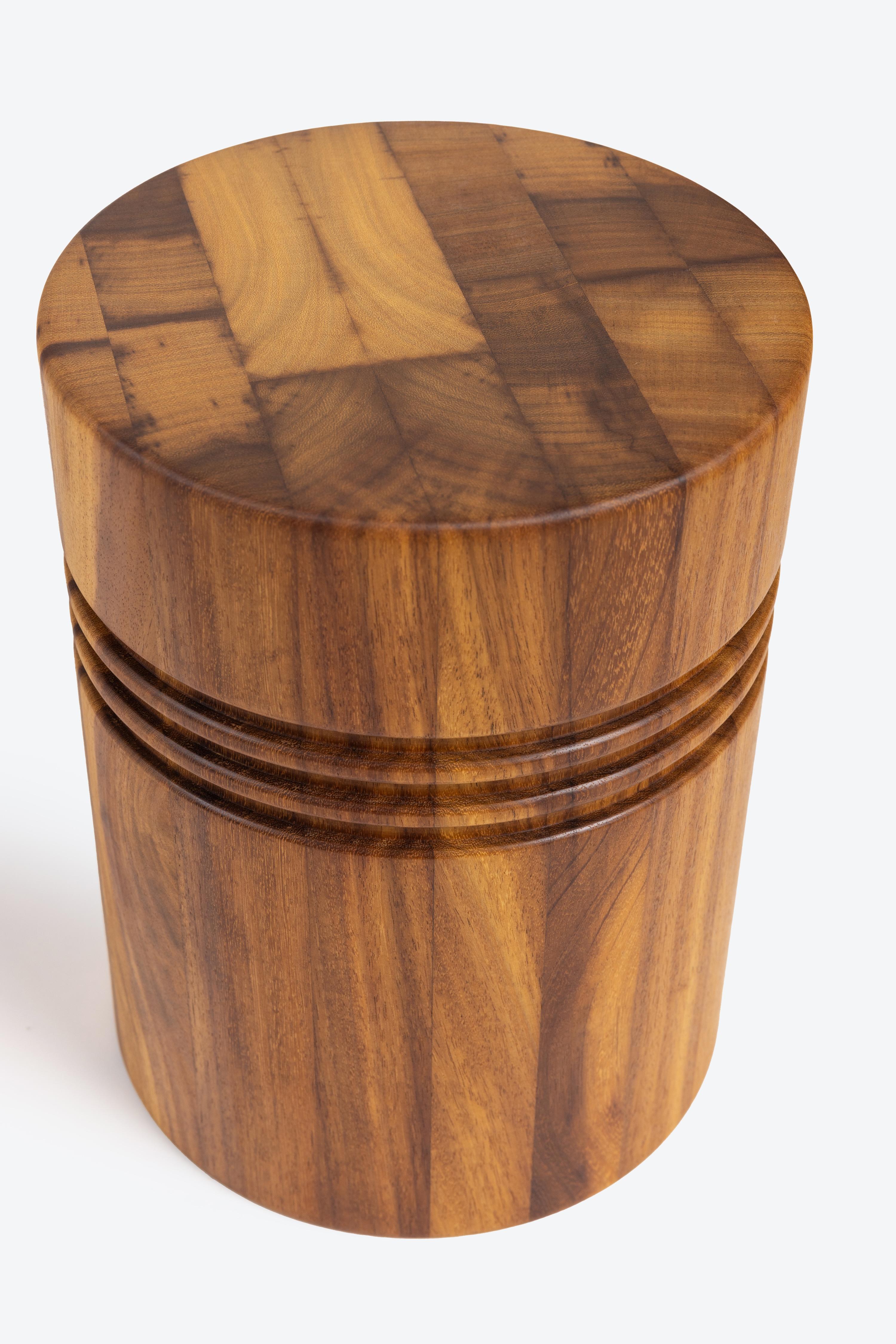 A solid wood stool turned on the lathe with three tiers. It can be used for seating or as a side table. It stands at 16 inches tall x 12 inches in diameter and weighs roughly 35 pounds. Made from Iroko wood. Each stool is unique based on the