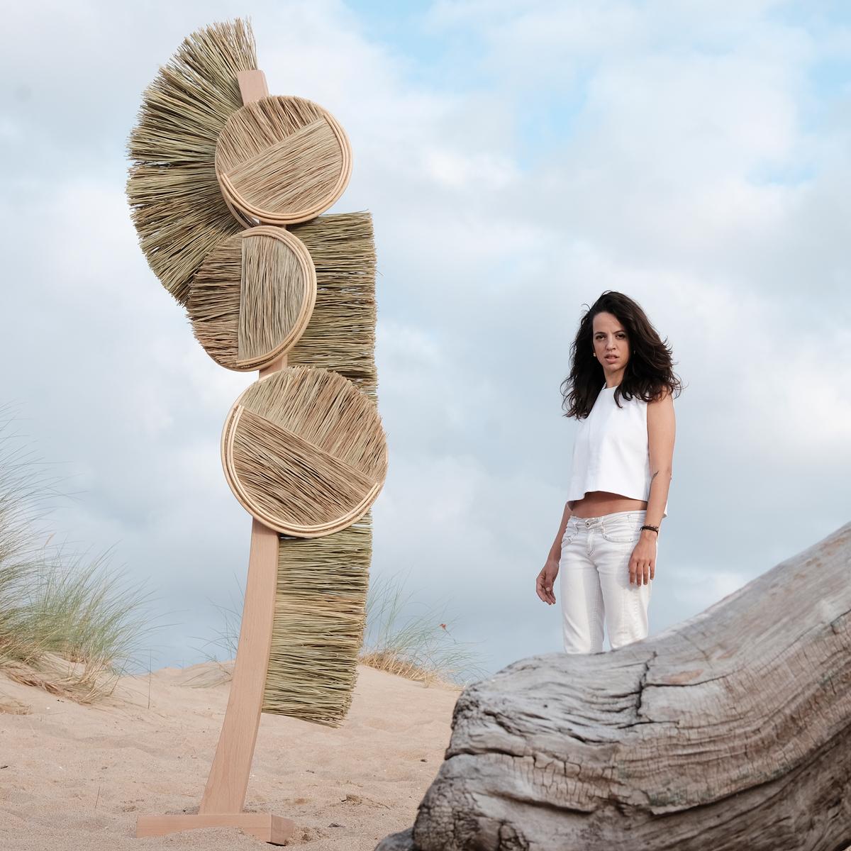An organic modern abstract sculpture crafted in Spain by Gabriela de Sagarminaga. This sculpture is handcrafted with esparto grass and topped with strips of pith. The pole and the platform where it sits are made of beech wood. This sculpture has