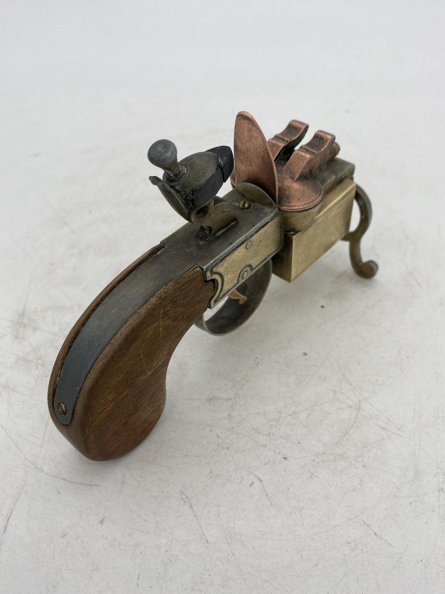 This Dunhill Tinder Pistol is a fine example of an extraordinary table lighter which is in the shape of a flintlock tinder (gun) pistol from the XVIII century.
It is made of brass and it has an antique brass finish and a nice oak slab handle