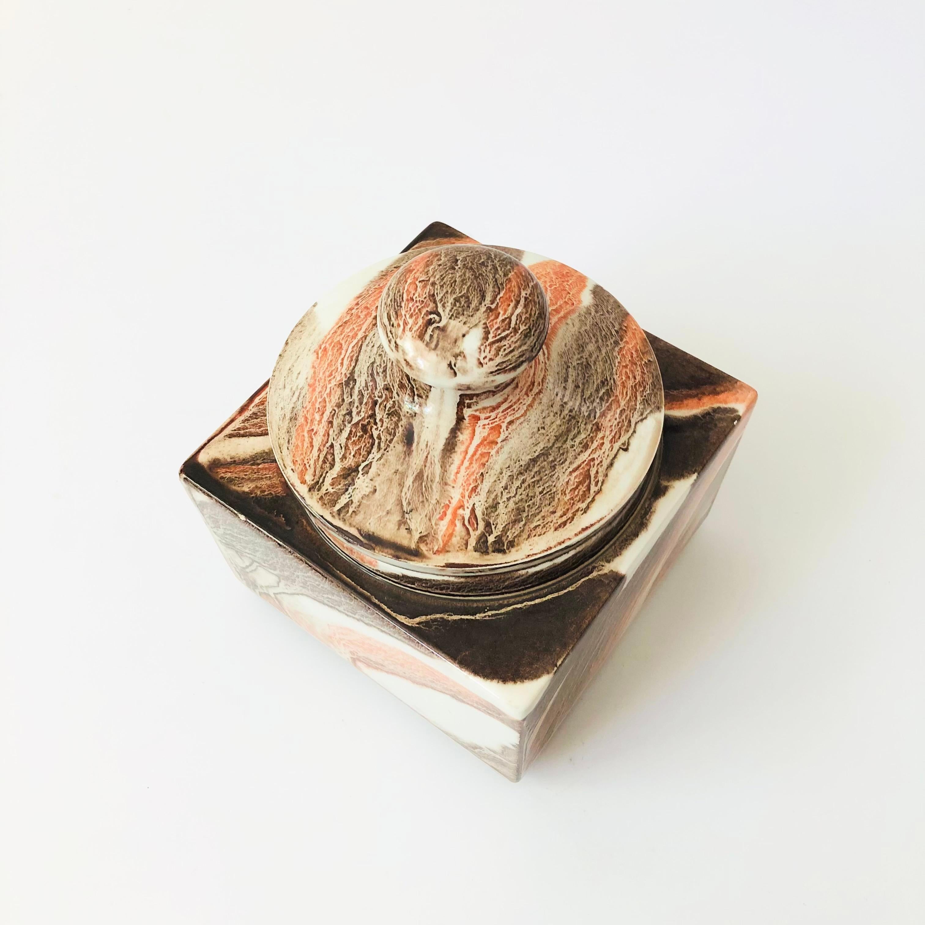 A vintage ceramic lidded container by Dunhill. Made in Italy. Square shape with a beautiful brown, pink, and white marble pattern to the glaze. Rubber gasket along the interior rim of the lid. Marked by Dunhill on the bottom.

