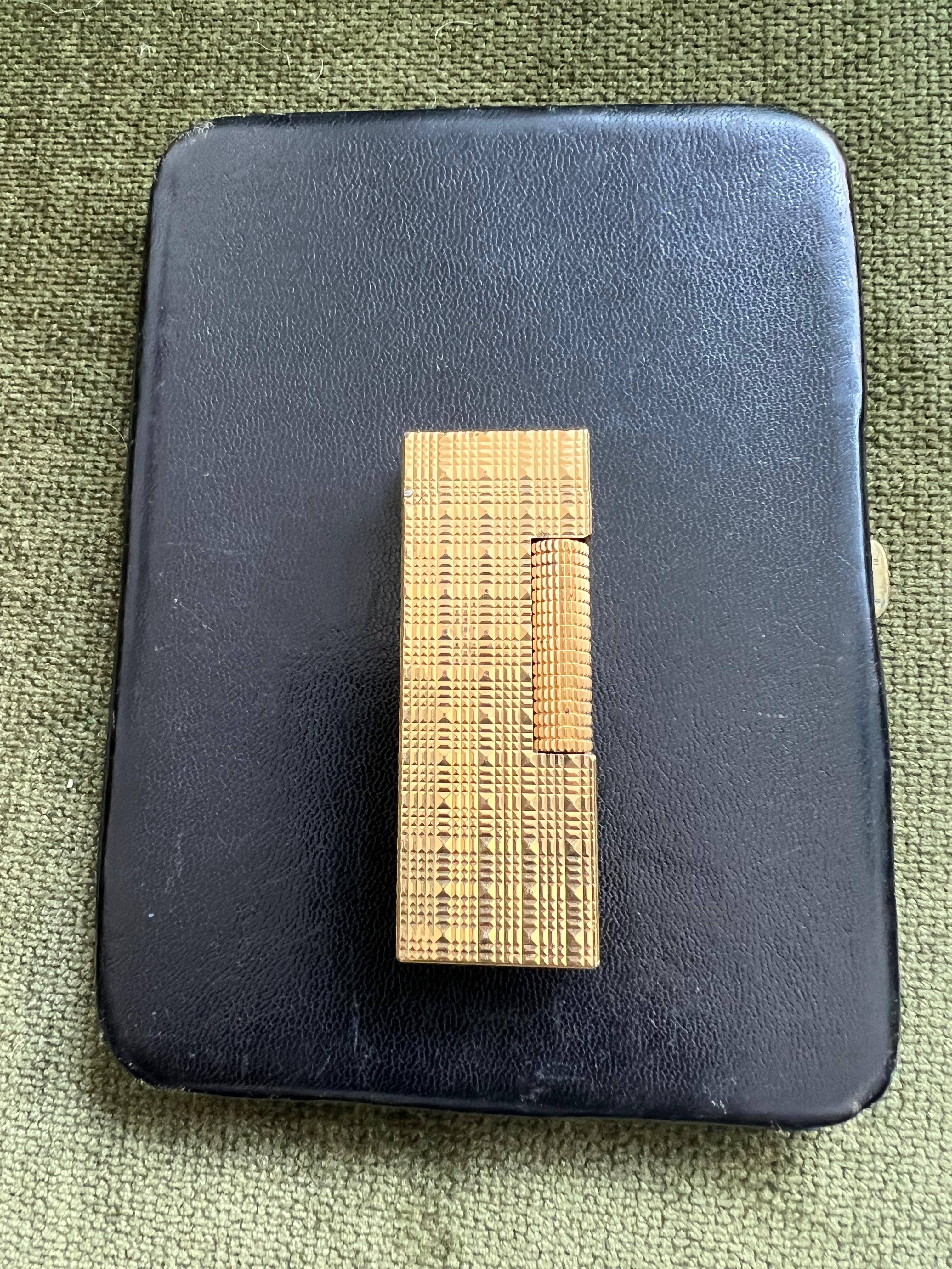 Dunhill Cigarette Case & Dunhill Gold Lighter Set, Vintage Circa 1970
The Cigarette case is made from hand made bound black lather with green satin interior. The case is in fantastic vintage wear condition. The clasp snaps to open and close.