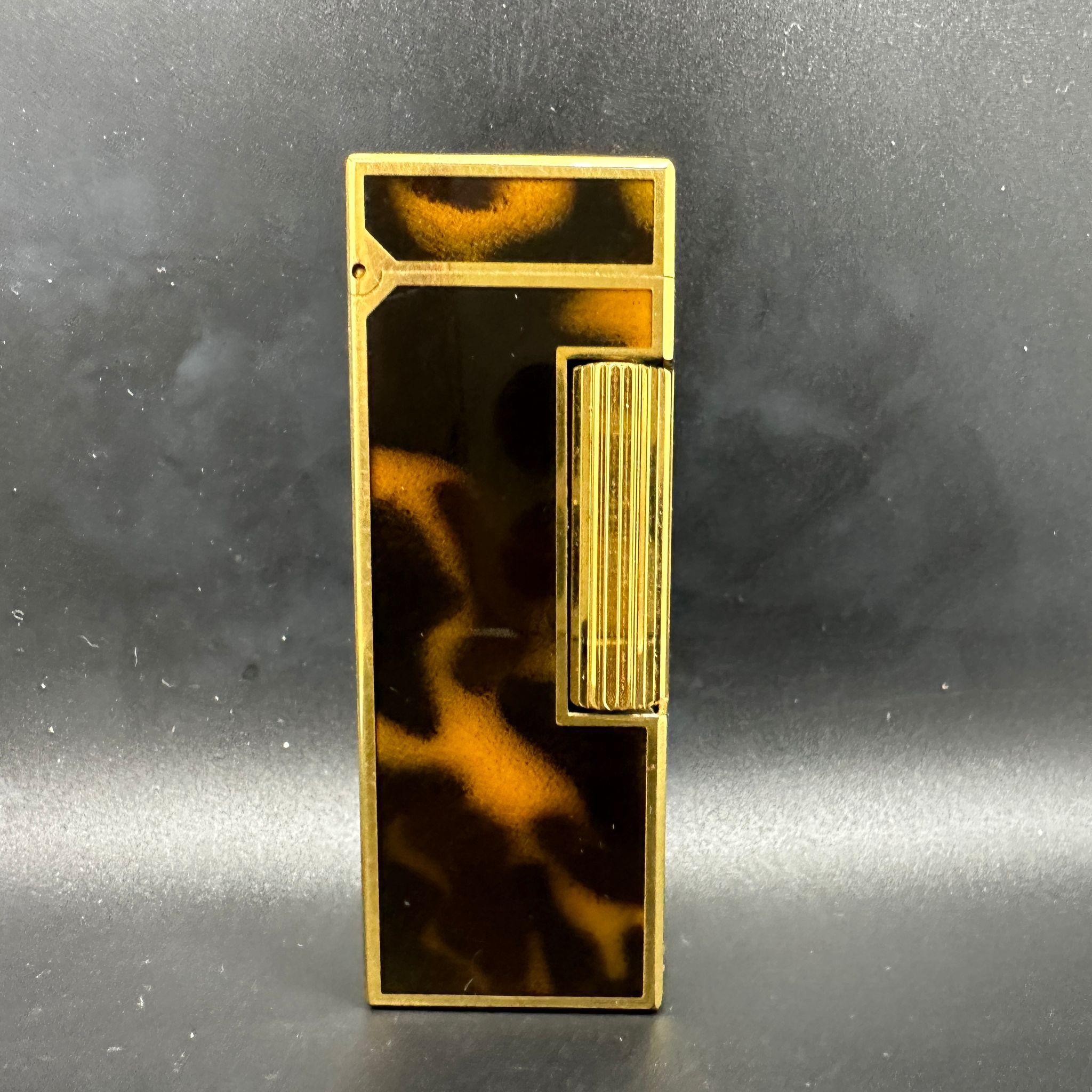 1980 Dunhill Gold Tone and Tortoiseshell Resin Rollagas Lighter
Circa 1980
Alfred Dunhill made lighter
Original Dunhill box and papers 
Chocolate velvet interior 
The lighter sparks, ignites and flames 
Retro and Rare 
