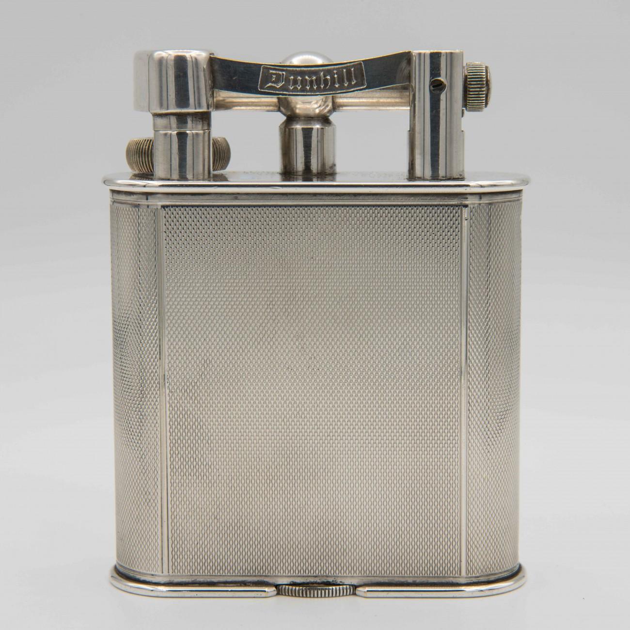 An engine turned silver plated Dunhill 'Giant' lighter; circa 1948. The 'Giant' table lighter was first seen in the Dunhill catalogue in 1929 and was an immediate success.

Dimensions: 10.5 cm/4 inches (height) x 8 cm/3? inches (width) x 2.5 cm/1