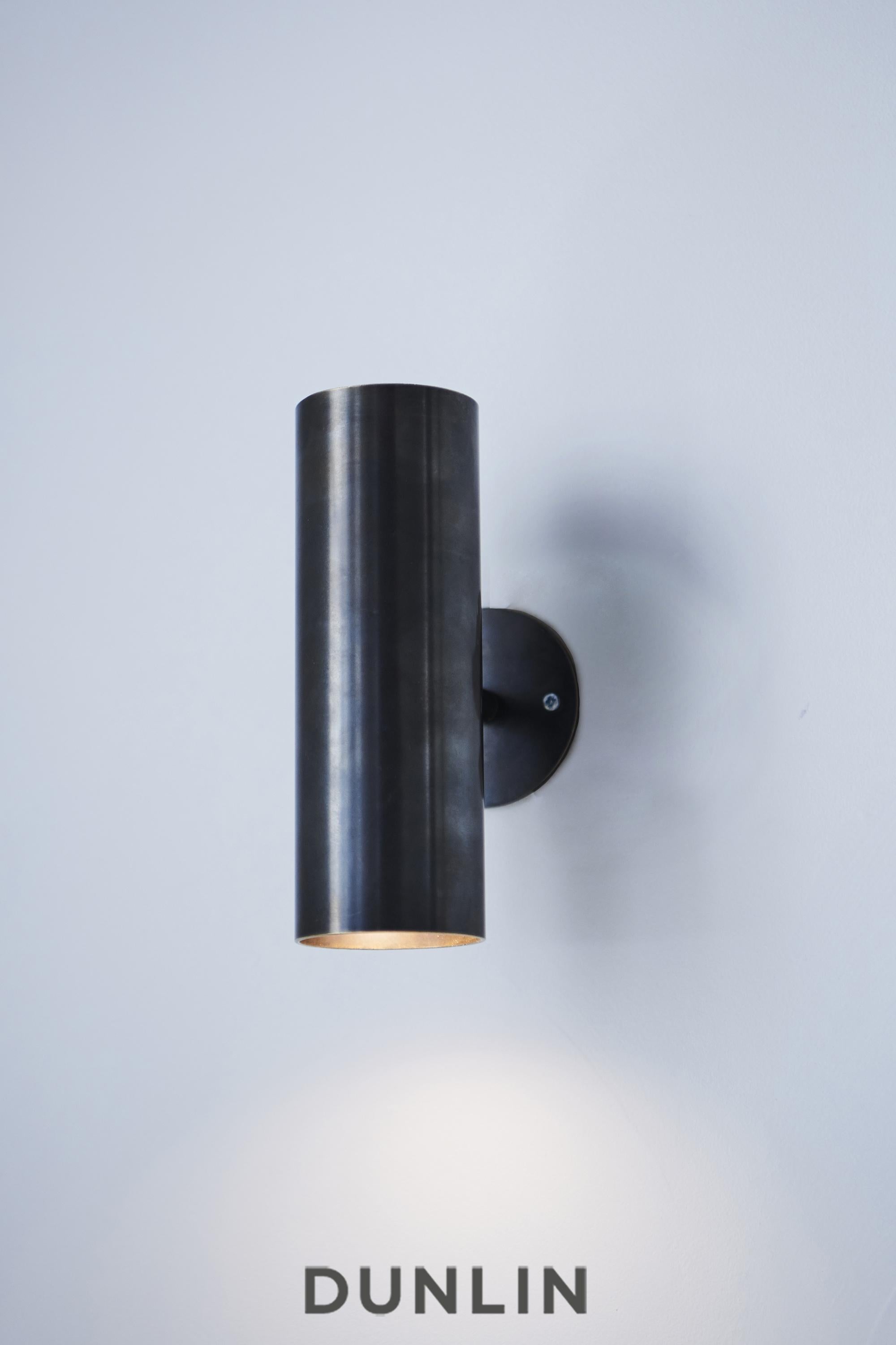 Handmade in solid brass in Australia by Dunlin. 

A playful up-down light in solid brass.
6.3 cm Diameter x 22 cm Long
Finish: Noir
Two lamp holders direct light vertically up and down, or sideways if installed horizontally. ( Globes not