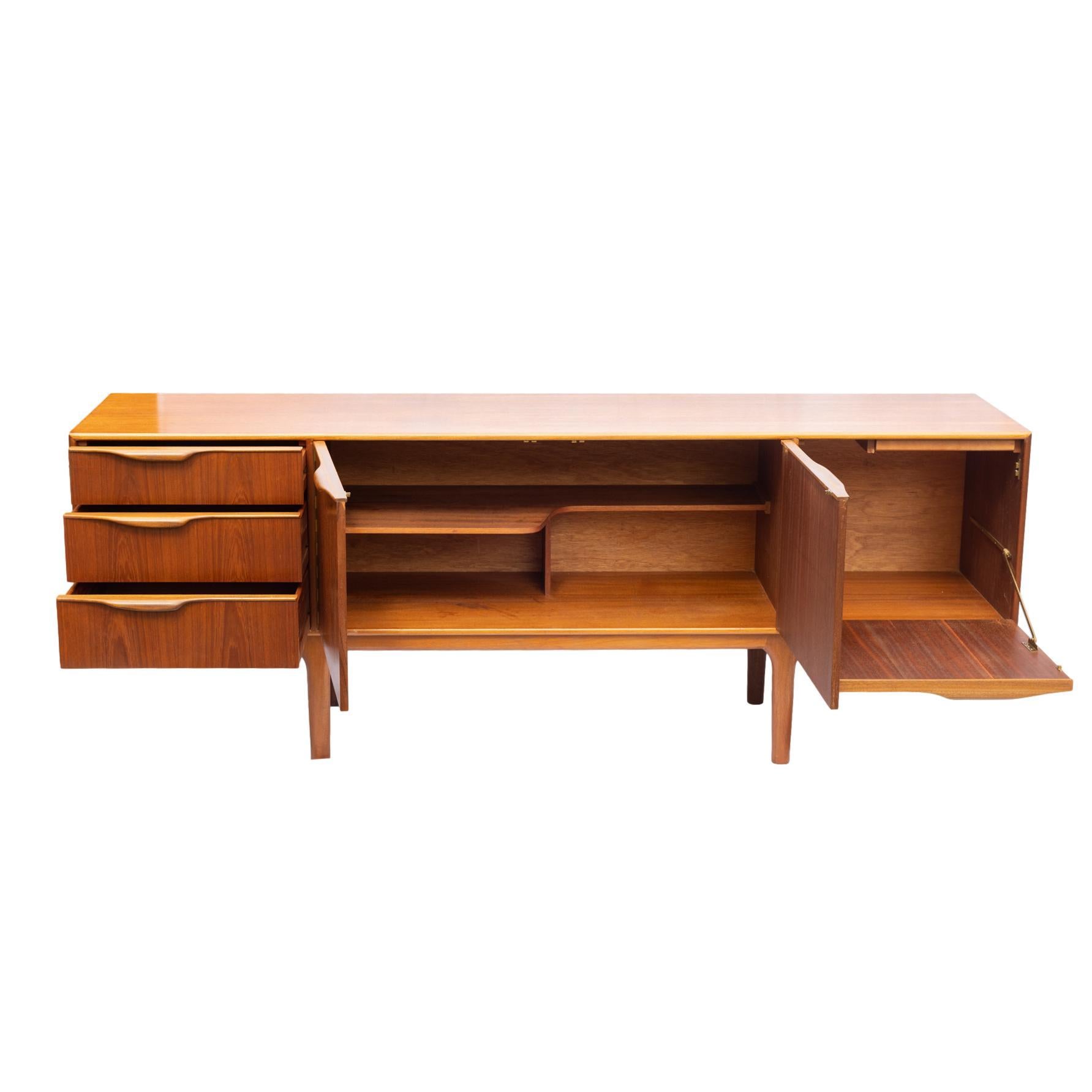 Mid-Century Modern Teak and Oak Sideboard, the streamlined form with two figured teak central cabinets, flanked by a row of three drawers and a bar cabinet with a cocktail slide, with molded and applied sculptural bars forming the pulls, on a Danish