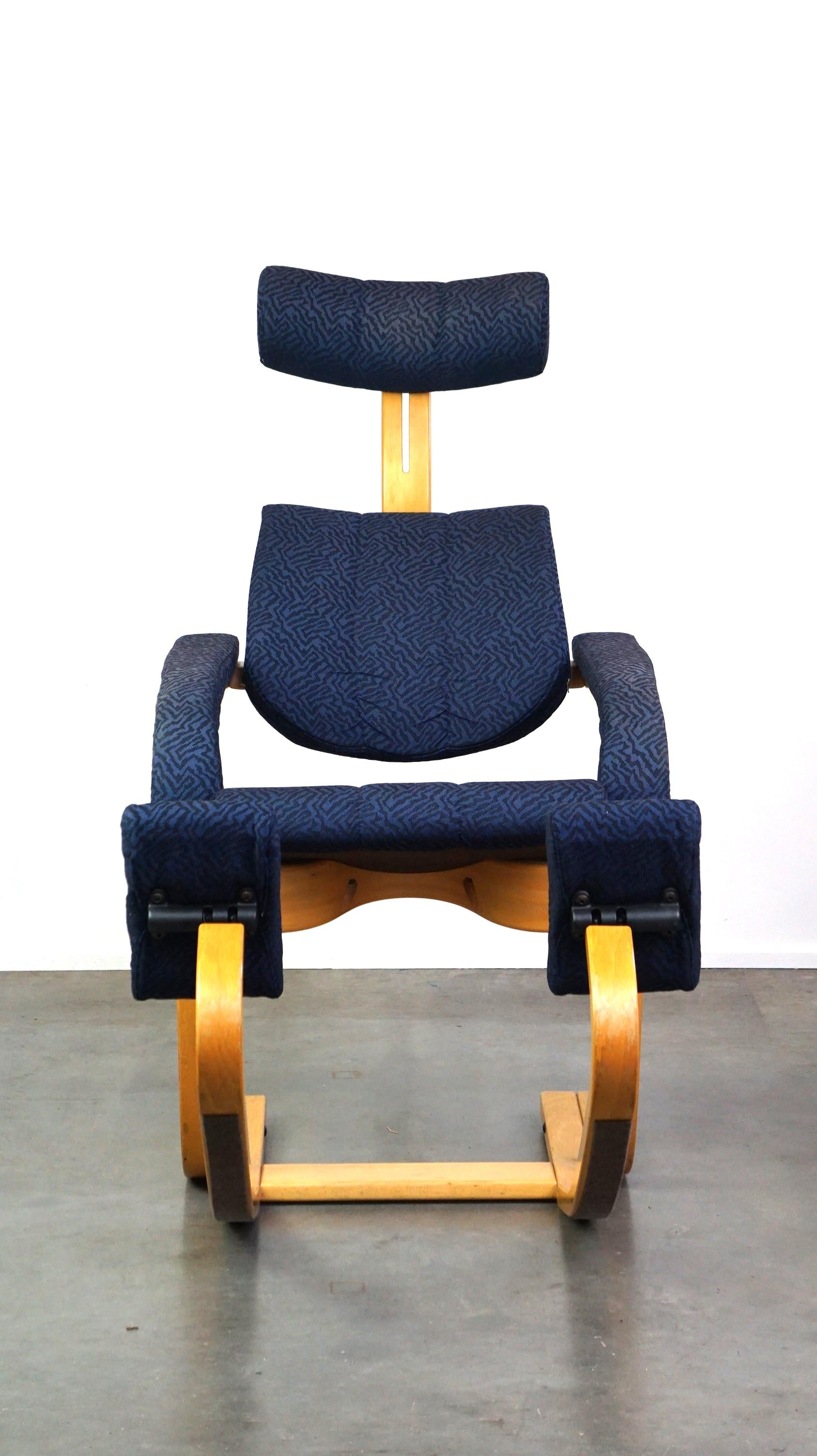 Dies ist der von Peter Opsvik entworfene und von Stokke hergestellte Arbeitsstuhl Duo Balance. Das ergonomische Design besteht aus massivem, dampfgebogenem Buchenholz und ist mit dunkelblauem Stoff gepolstert. Der Stuhl ist mit Stützpolstern für die