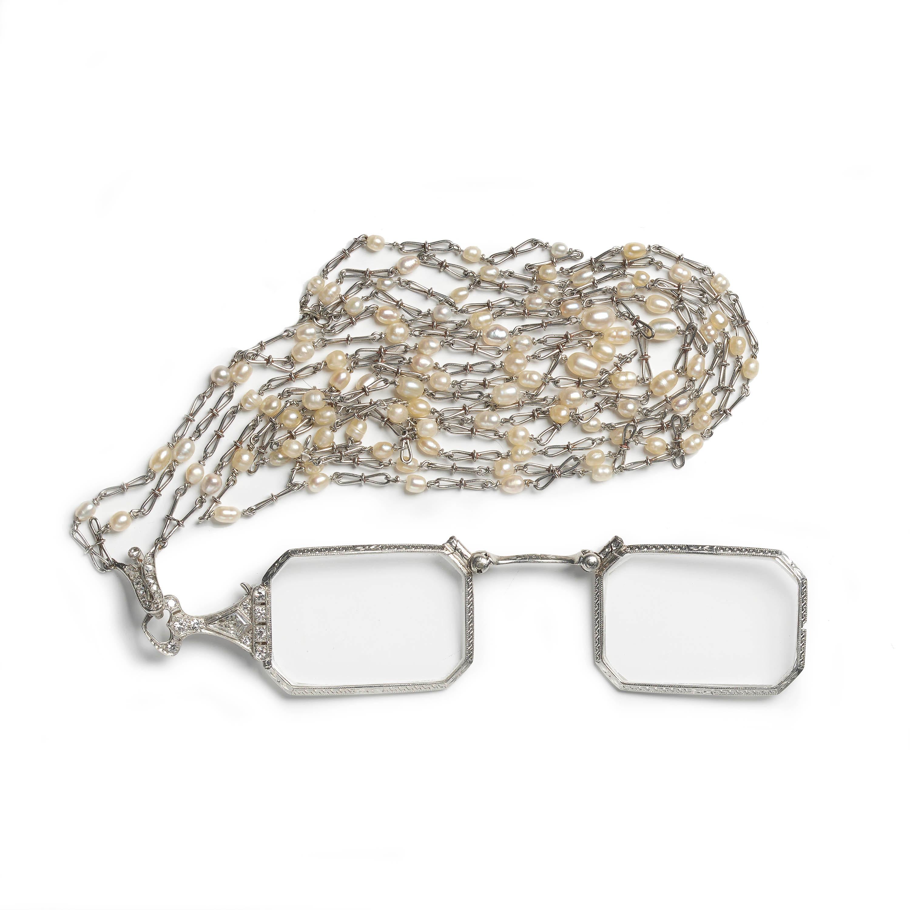 An Art Deco diamond set lorgnette, on a pearl and platinum double long chain, with cut corner rectangle lenses, in engraved and millegrain edged surrounds, with a handle set with a kite-shape diamond, surrounded by eight-cut and round brilliant-cut