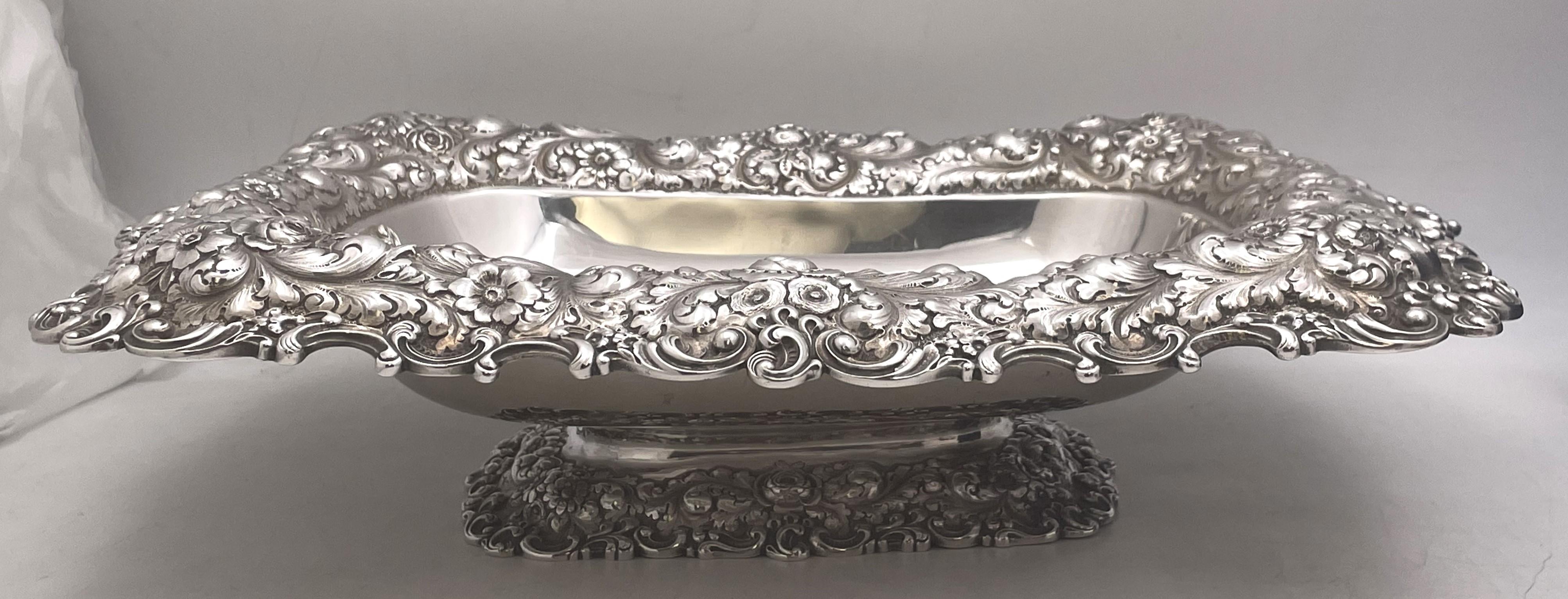Ciotola in argento sterling Durgin, venduta da Grogan, risalente alla fine del XIX secolo con un bordo ornato da disegni floreali e curvilinei in repousse. Misura 15'' di profondità, 12'' di larghezza e 4 1/3'' di altezza, pesa 50,9 once troy e reca