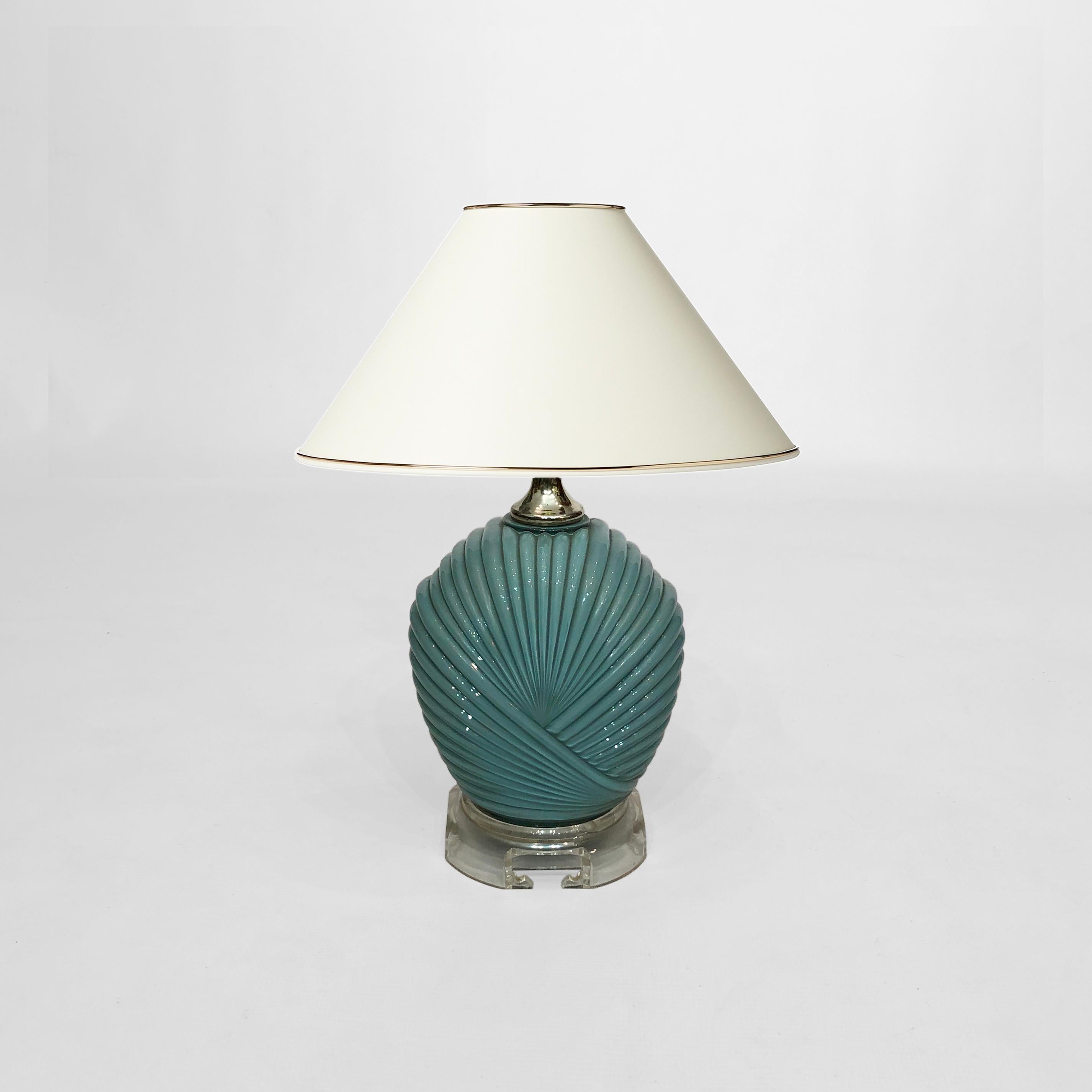 A petite dusty blue candy-style table lamp, in glass and acrylic, originating from USA in the 1970s. The body of this piece is in an Art Deco-inspired ridged glass shell pattern which is painted inside, making it look like candy. The lamp sits atop