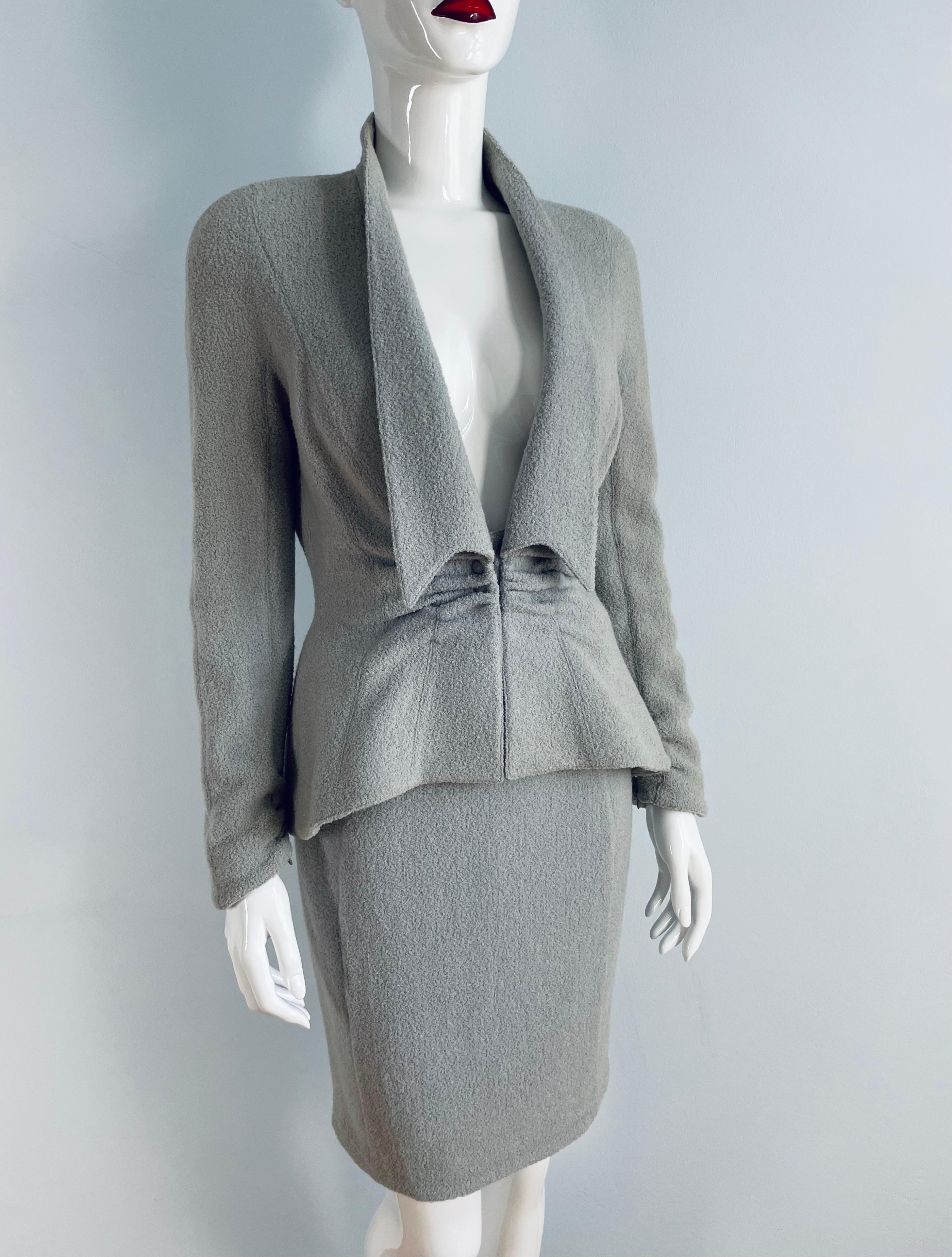 Staubblauer Thierry Mugler-Rockanzug aus den späten 1990er Jahren.
Der taillierte Schnitt von Mugler mit dramatischem Revers und tiefem V-Ausschnitt ist absolut umwerfend. 
Zusammensetzung: 88% Wolle, 12% Nylon. 
Zustand: sehr gut. 
Kein Label für