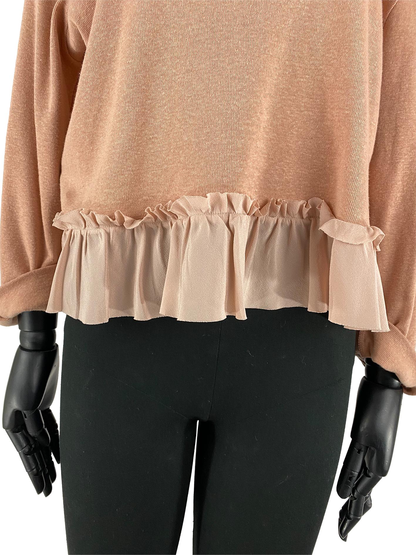 A dusty pink Miu Miu cotton top with silk ruffled detailing at the bottom in a pale pink colour. This top features a beige bow at the back with a V-shaped cut out just under. The sleeves are stylised in a rolled-up fashion; which is tacked to