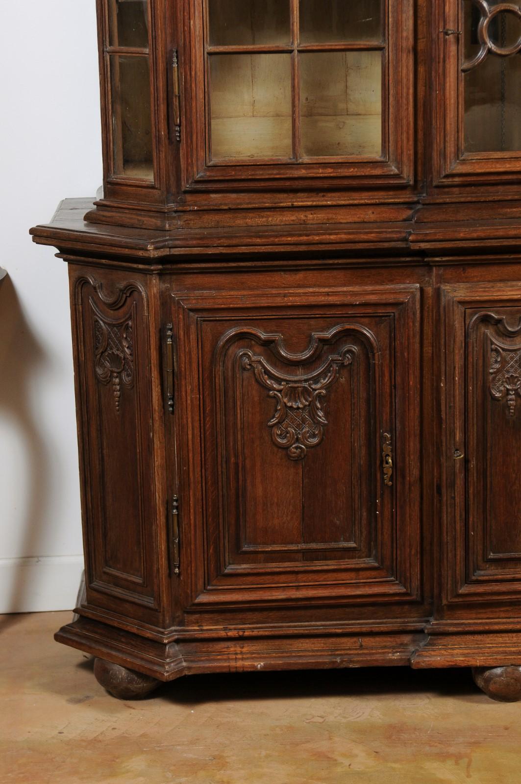 A Dutch oak buffet à deux-corps from the late 18th century, with glass doors, canted sides, carved panels and central clock. Born in the Netherlands during the last decade of the 18th century, this oak buffet à deux-corps features a bonnet-shaped