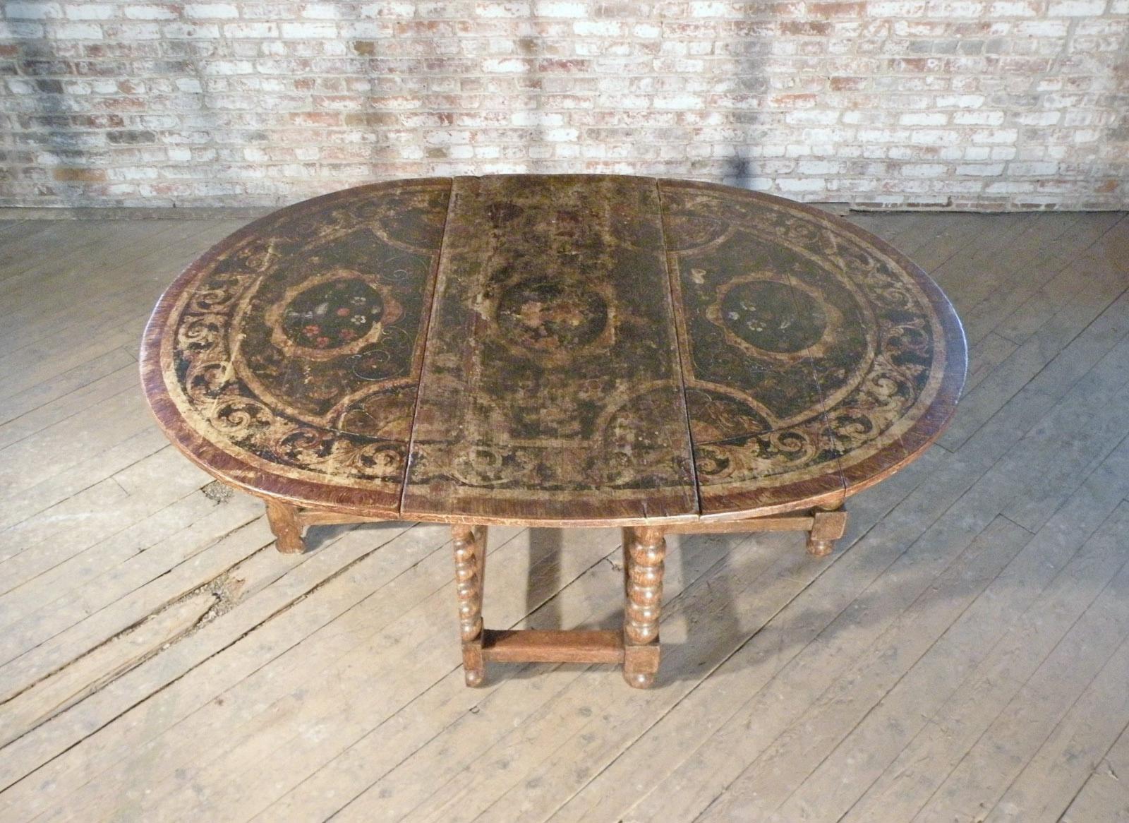 A charming Dutch Gate-Leg Table in original condition. The painted surfaces beautifully worn, the top with typical baroque scrolling foliage borders and floral center fields, the base faux-grain painted. Bobbin-turned legs with swing-out mechanism