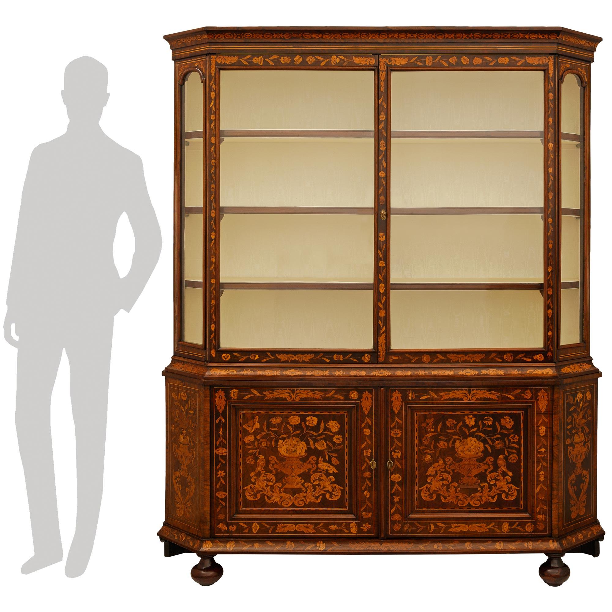 A wonderful and most decorative Dutch 18th century Walnut and Fruitwood cabinet vitrine. This exceptionally designed four door cabinet is raised by two square block back supports and front bun feet. The straight concave shaped inlaid frieze is