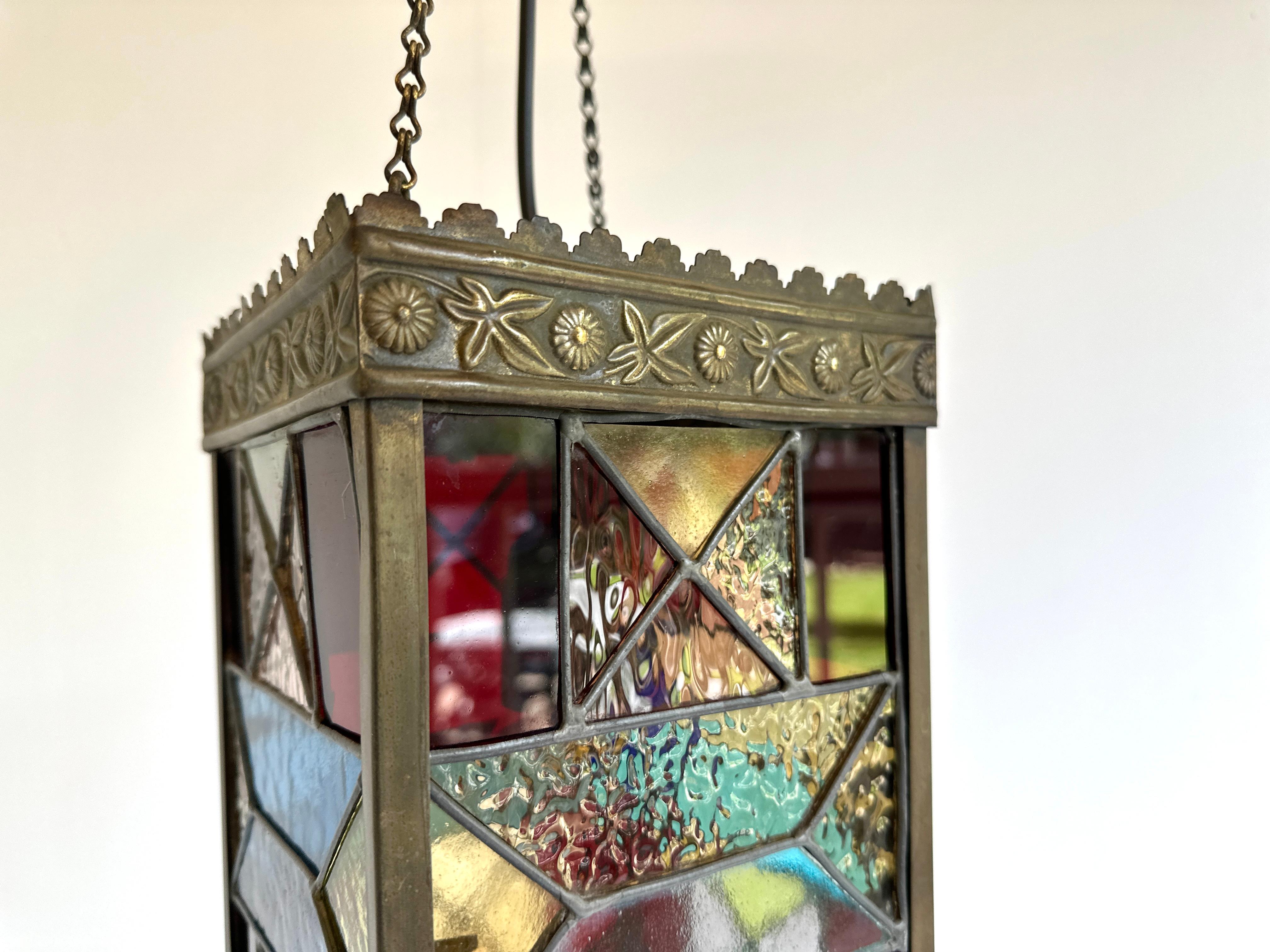 Introducing the strikingly beautiful 1920 Stained Glass Hallway Lantern. This Arts & Crafts style lantern is the perfect addition to any home that appreciates the beauty of handcrafted glass. With brilliant jewel-toned hues and intricate geometric