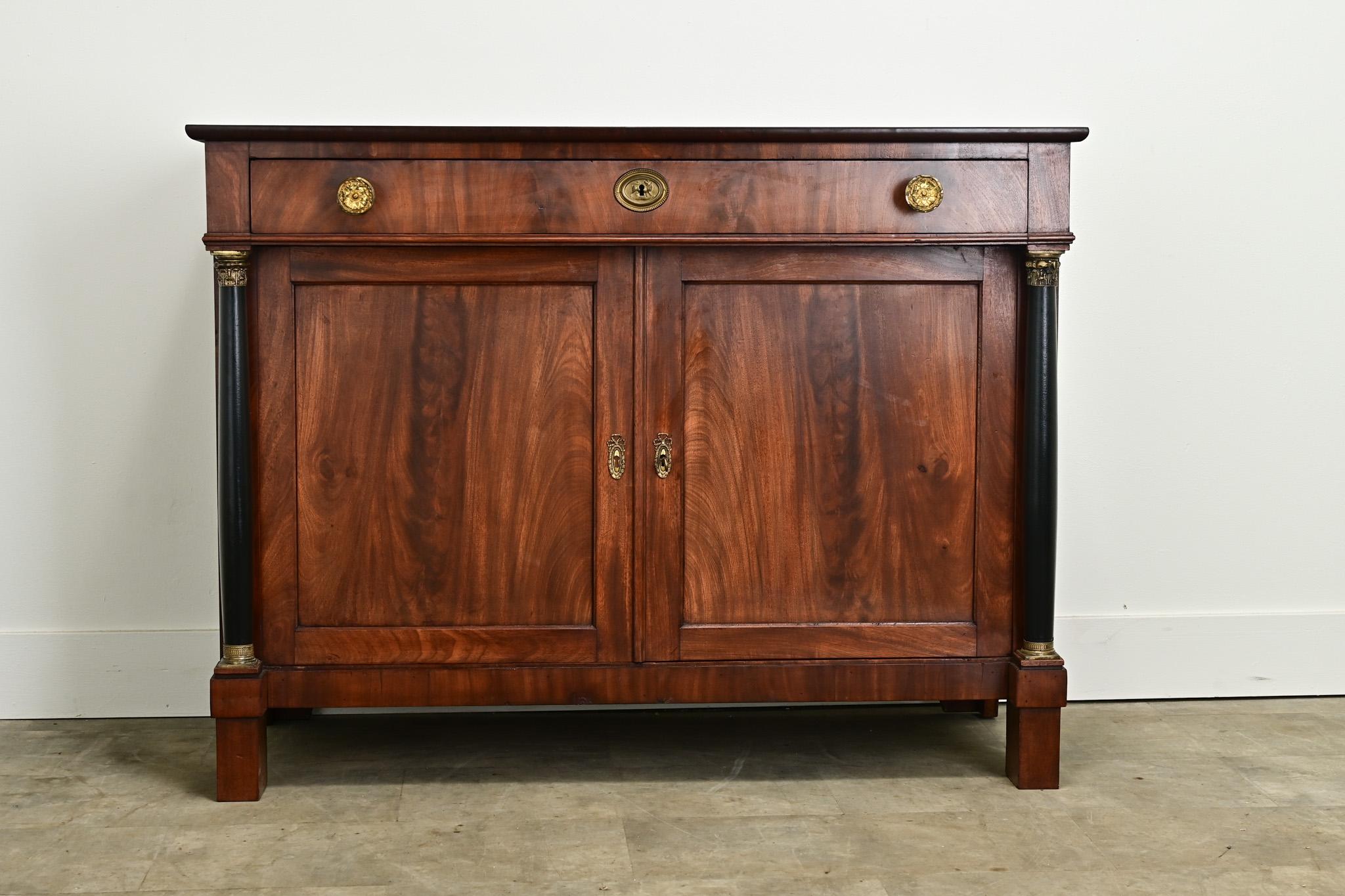 A handsome Dutch Empire buffet made of walnut with ebonized details. The top of this cabinet is made of walnut and has two extending shelves on each end for additional surface area. Below is a long single drawer with large brass knobs. The center of