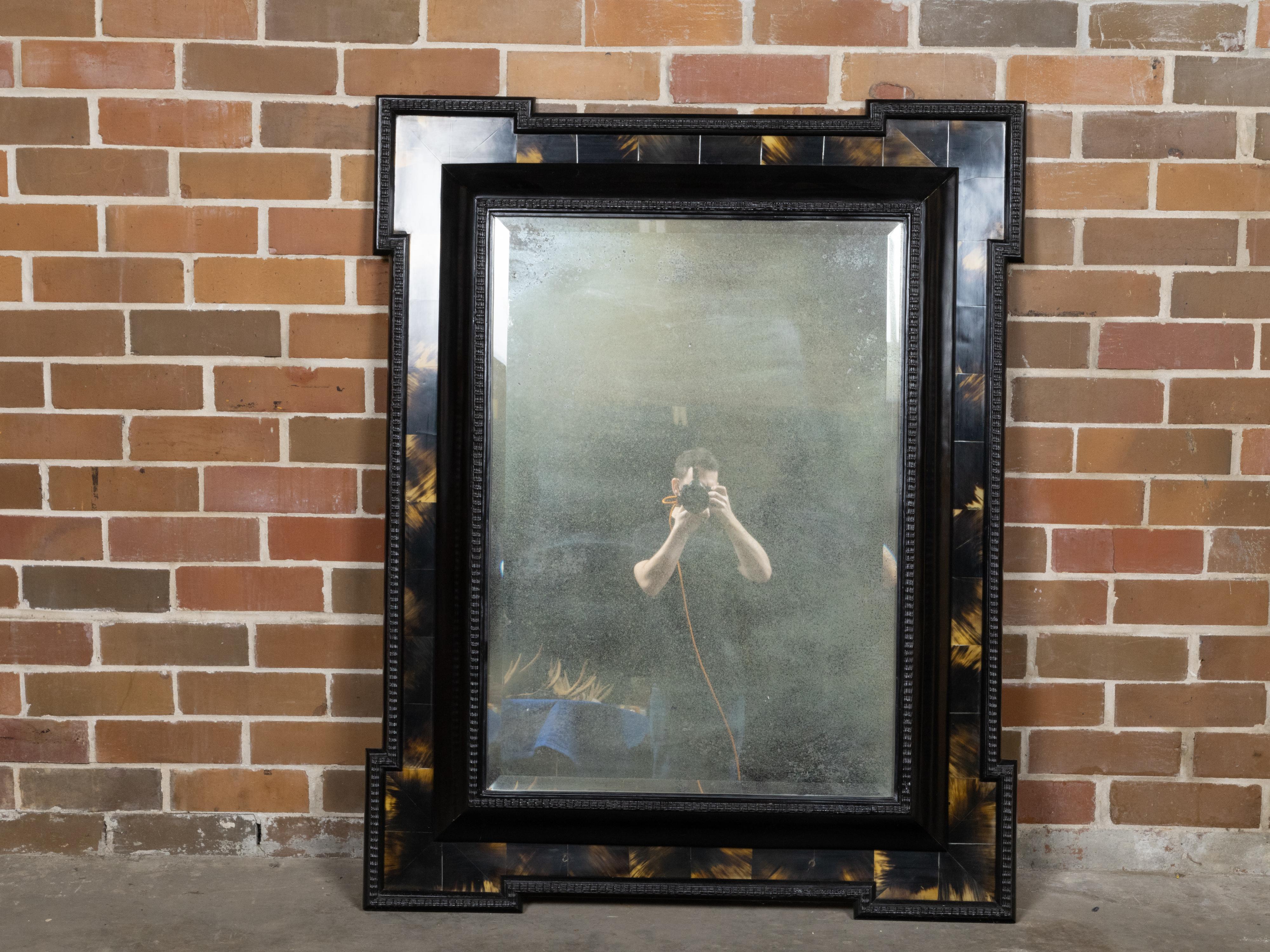A Dutch faux tortoise black wall mirror from the 19th century with amber accents, carved frame and protruding corners. Enhance your home decor with this exquisite Dutch faux tortoise black wall mirror from the 19th century. Crafted with meticulous