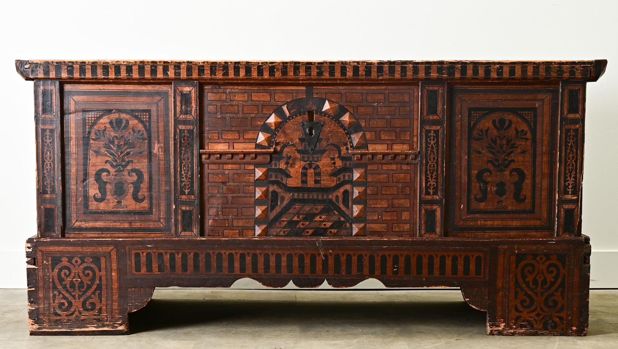A unique large  pine trunk from Holland with its original paint finish. The front side has a painted design of a castle with a faux brick pattern and stylized windows over a playful scalloped apron, flanked by floral geometric patterns. The top