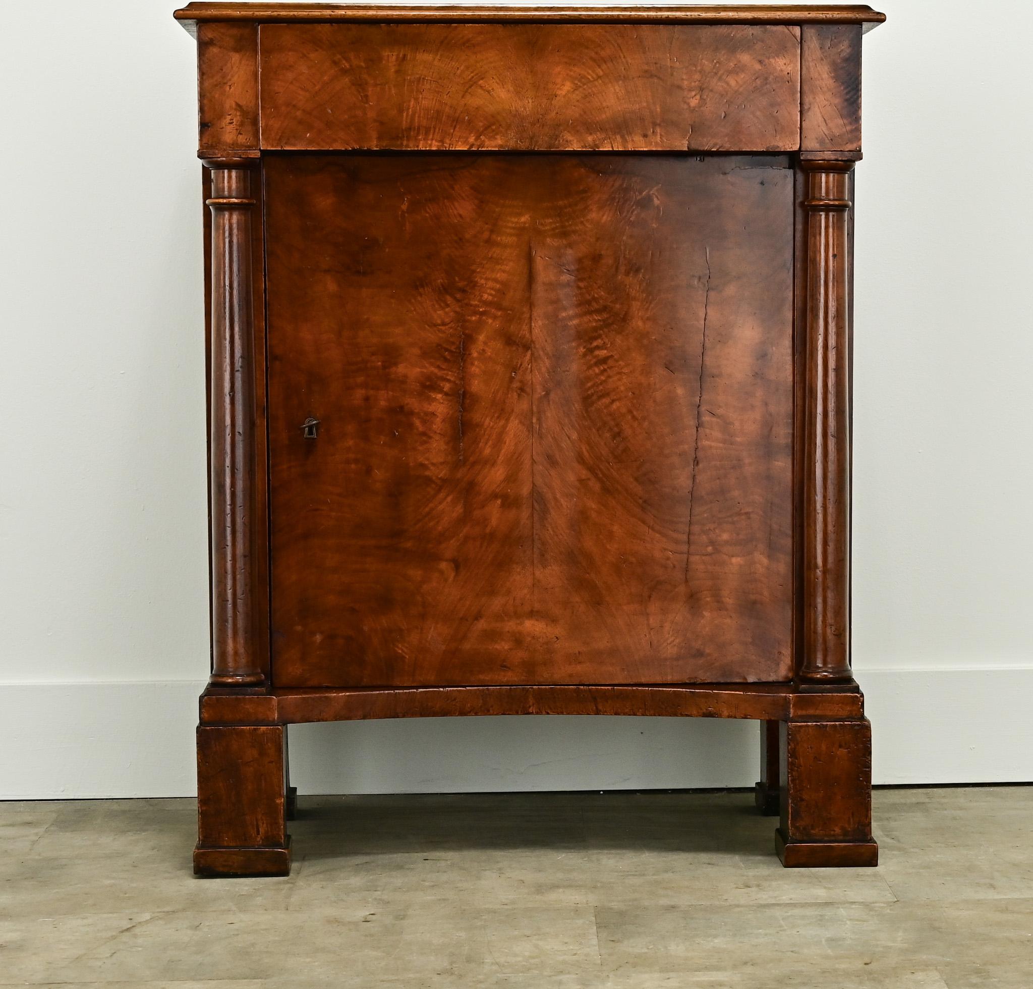 A unique walnut cabinet made in the Netherlands during the 1800’s. It has the clean lines of an English antique in the style of the French Empire and is made of solid burl walnut. A simple walnut top sits over a single drawer and door flanked by