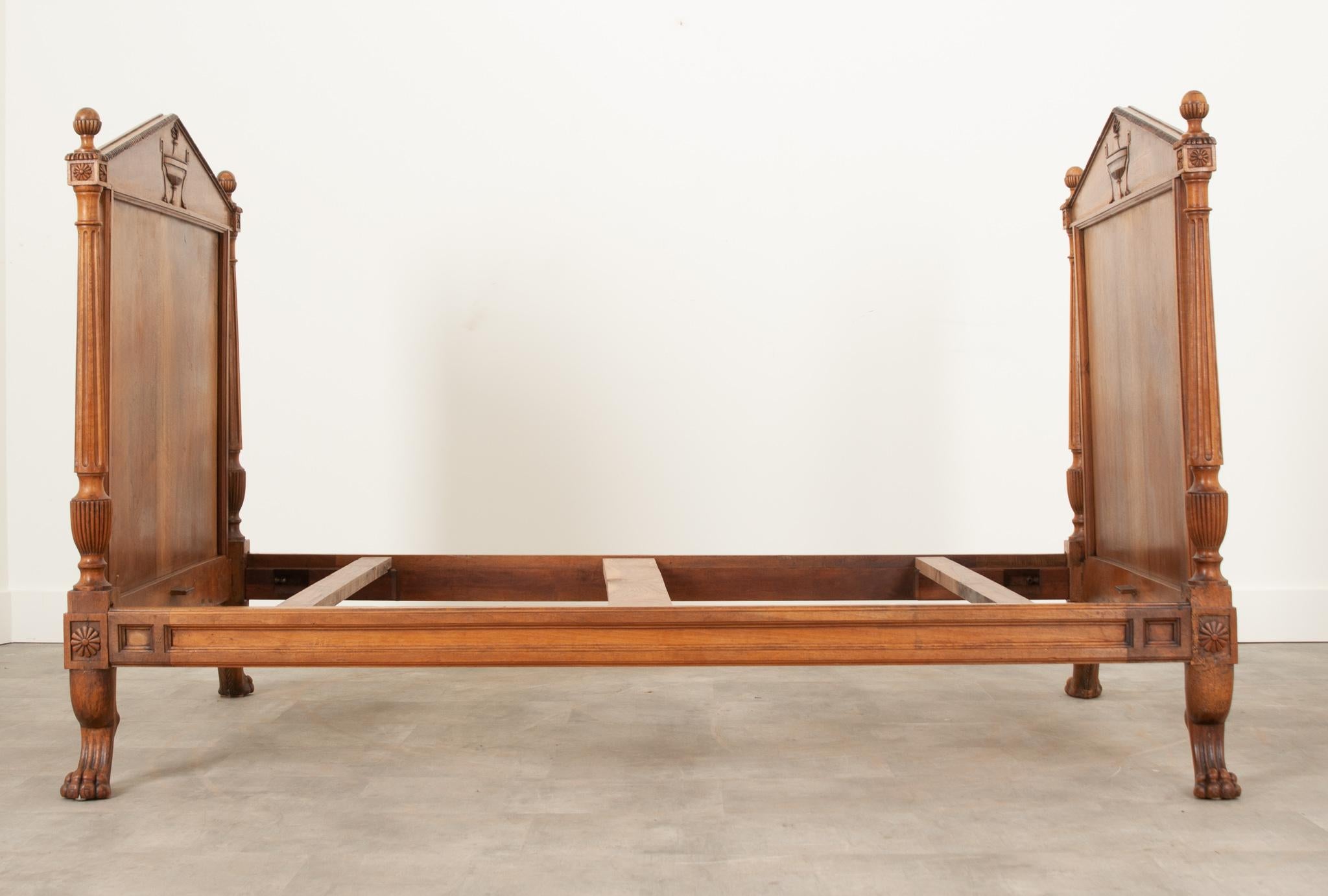 A fabulous walnut daybed with stately presence from 19th century Netherlands. The bed’s head and foot boards are topped with pediments featuring beautifully carved tazza style urns. The urns have handles that loop and extend to the ground with paw