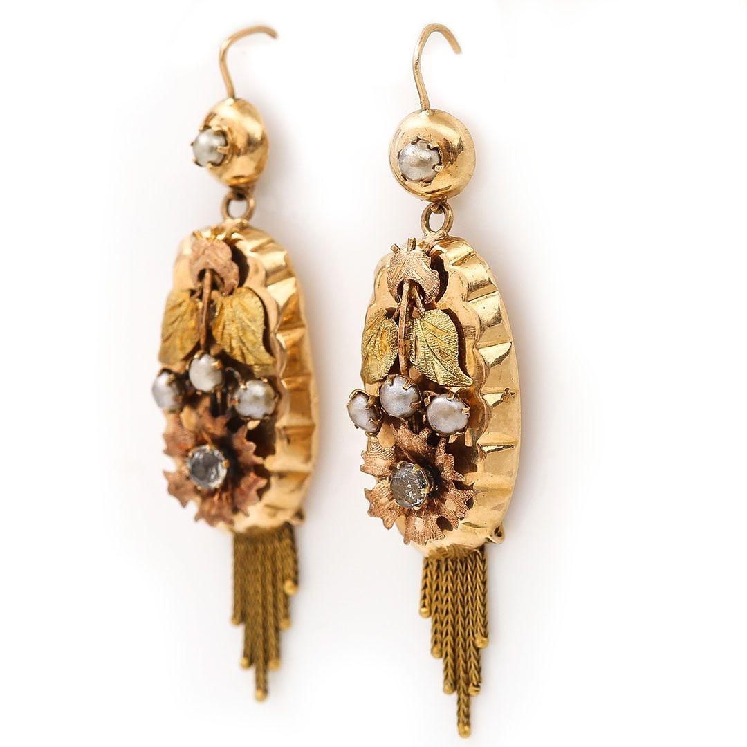 A wonderful pair of antique drop earrings dating from the 19th century and originating from the Netherlands adorned with split pearls and rhinestones. The body of the earrings are surmounted with rose and yellow gold finally chased leaves and flora