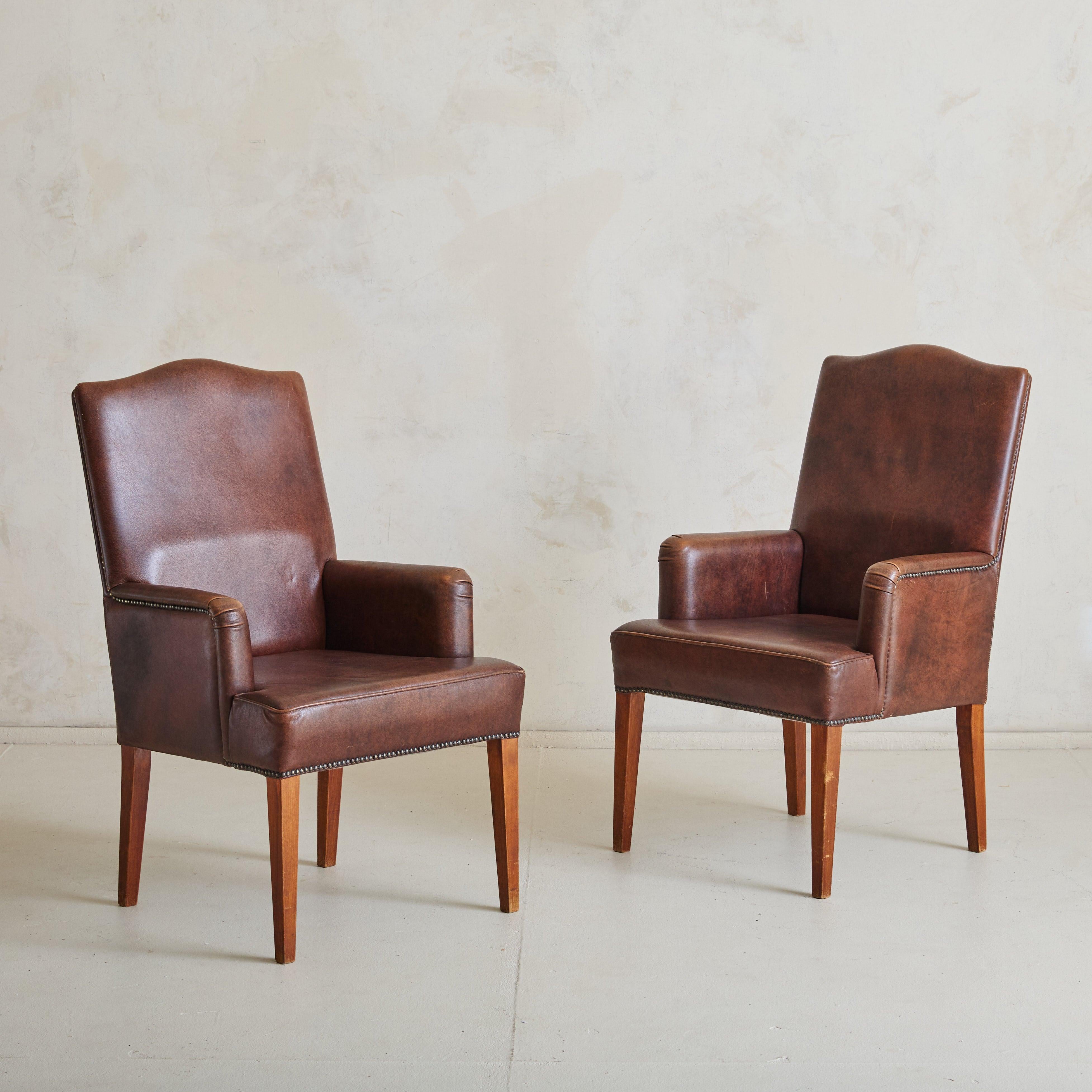 A Dutch armchair from the 1970s, upholstered in rich sheepskin leather with a warm patina and supple texture. Tapered, solid wood legs offer sturdy support, while original nailhead detailing frames the chair, accentuating the low arms and softly