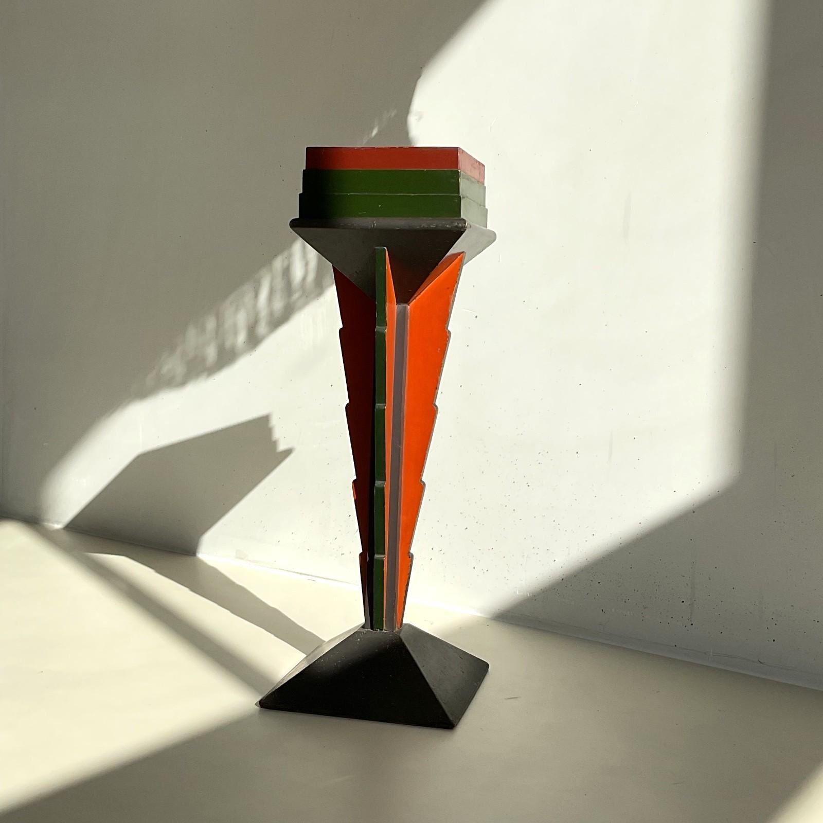 Un pedestal o soporte para plantas grande y colorido,  época muy reconocible de la Escuela de Amsterdam, años 20. Los colores de la pintura son muy similares a los de la pintura de Jan van Zeeland, un diseñador del periodo Art Déco holandés que  es