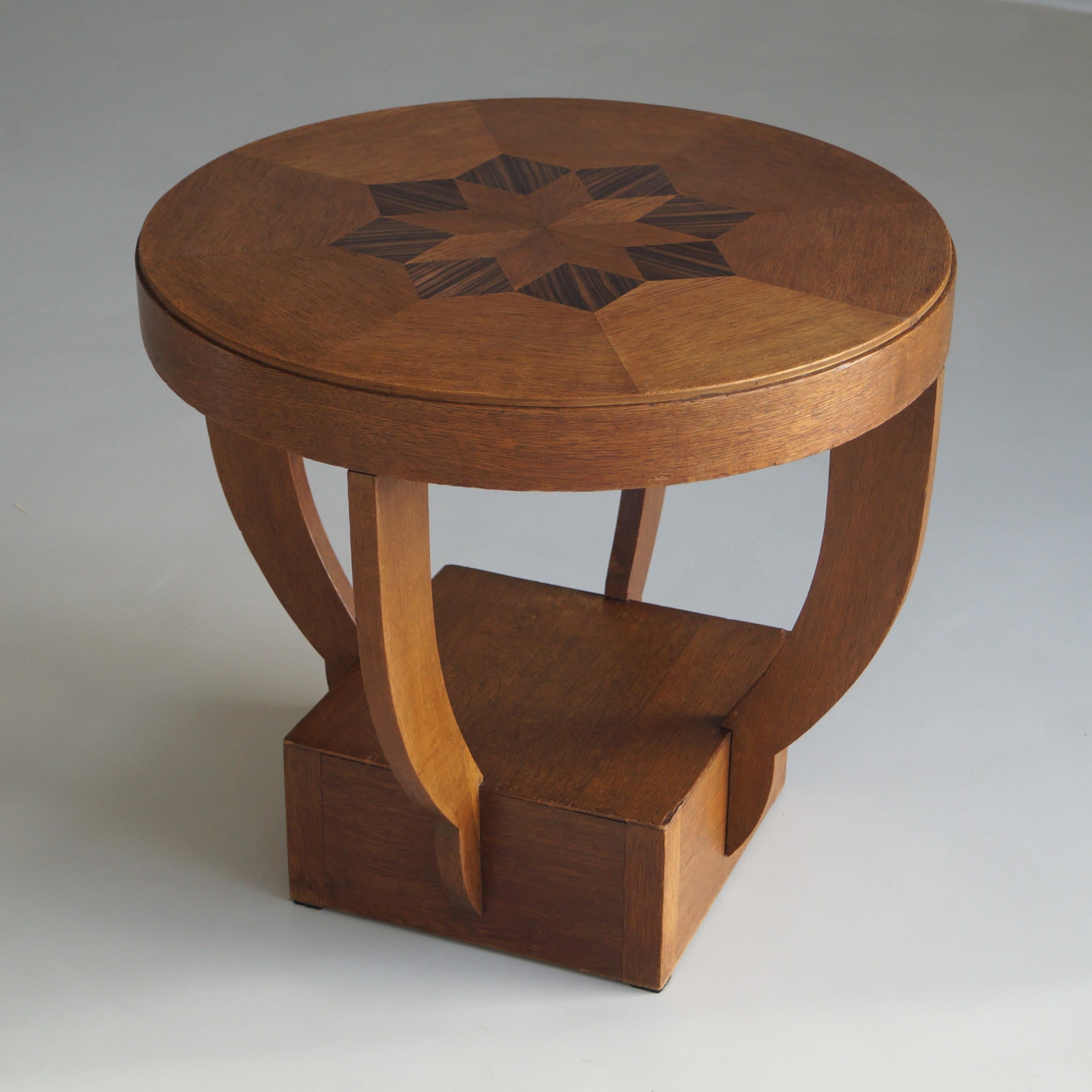 Una mesa auxiliar decorativa de roble con un dibujo de ébano de macassar en forma de estrella en el tablero. Tiene un tamaño modesto (adecuado como mesita de café) y poco desgaste para su edad (fabricada a mano en los años 20). Tiene algunos