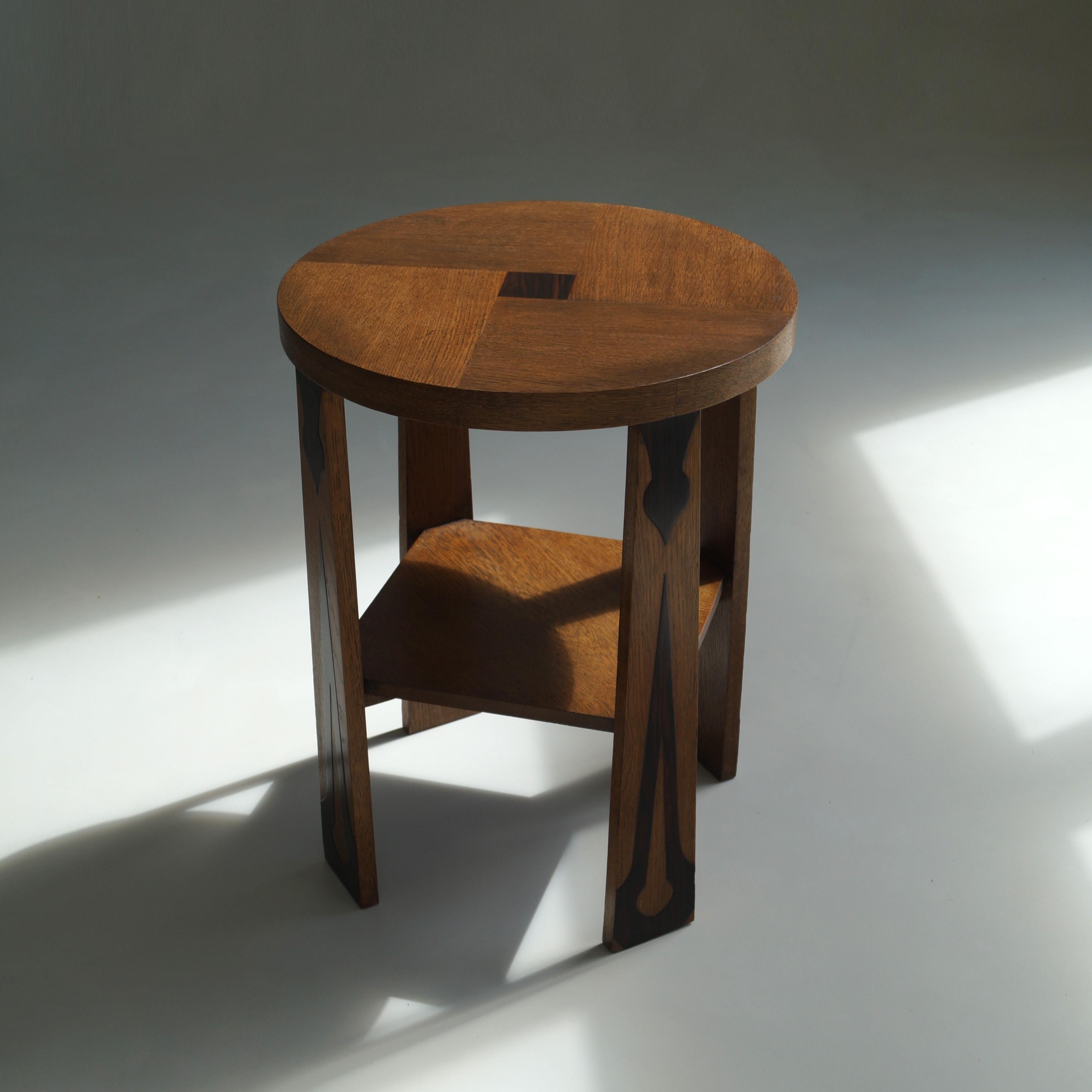 A Dutch 1920s occasional table in oak and macassar ebony details. 

This piece is in very good condition, heavier than one would expect and very sturdy and stable. The decorative motifs seen on the four tablelegs in macassar ebony are characteristic