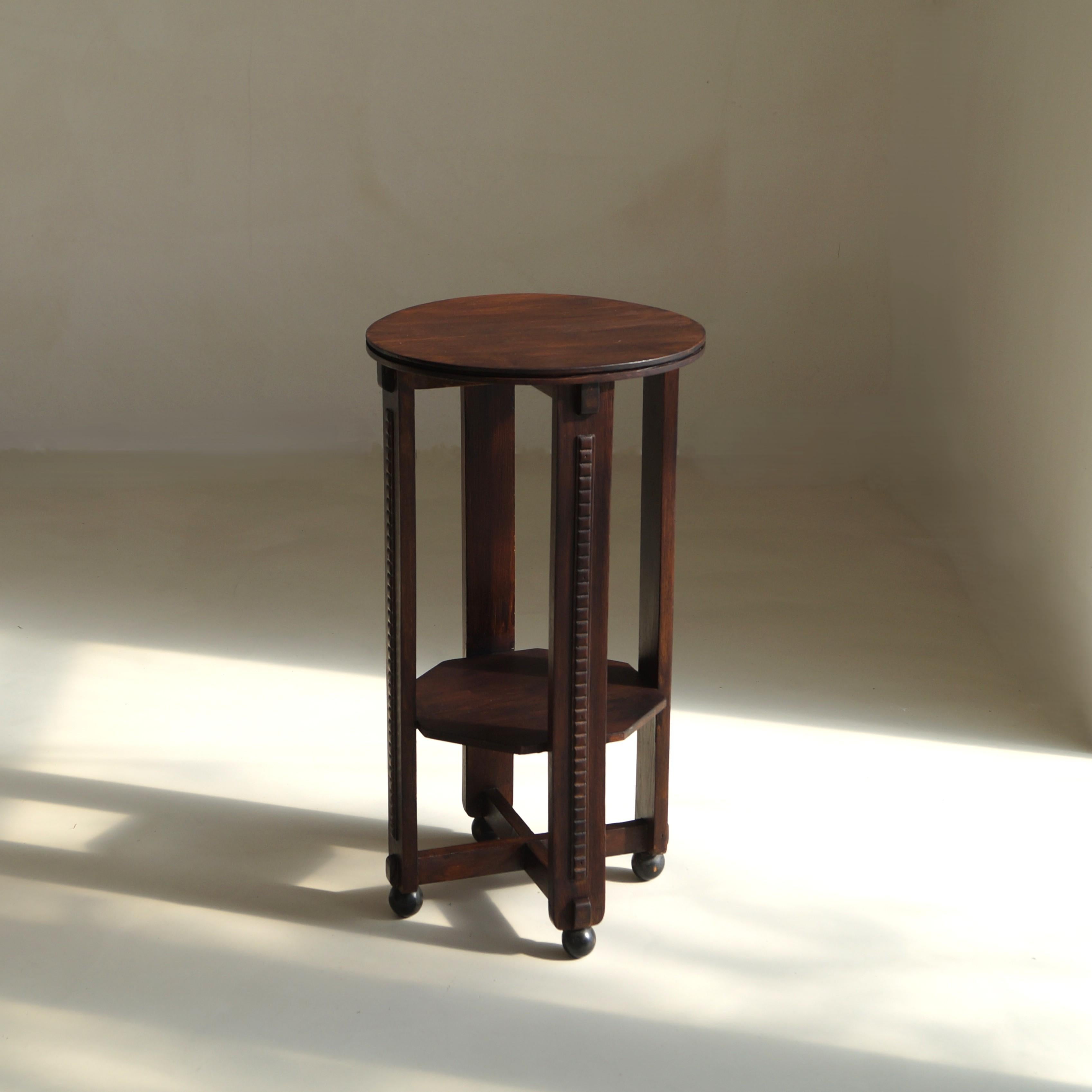 A dark-stained oak occasional table or plant pedestal dating to around 1925, reflecting the Amsterdam School language that swept Dutch interiors in the 1920s.

The table has nice features - the decorations that run down the four table legs, the ball