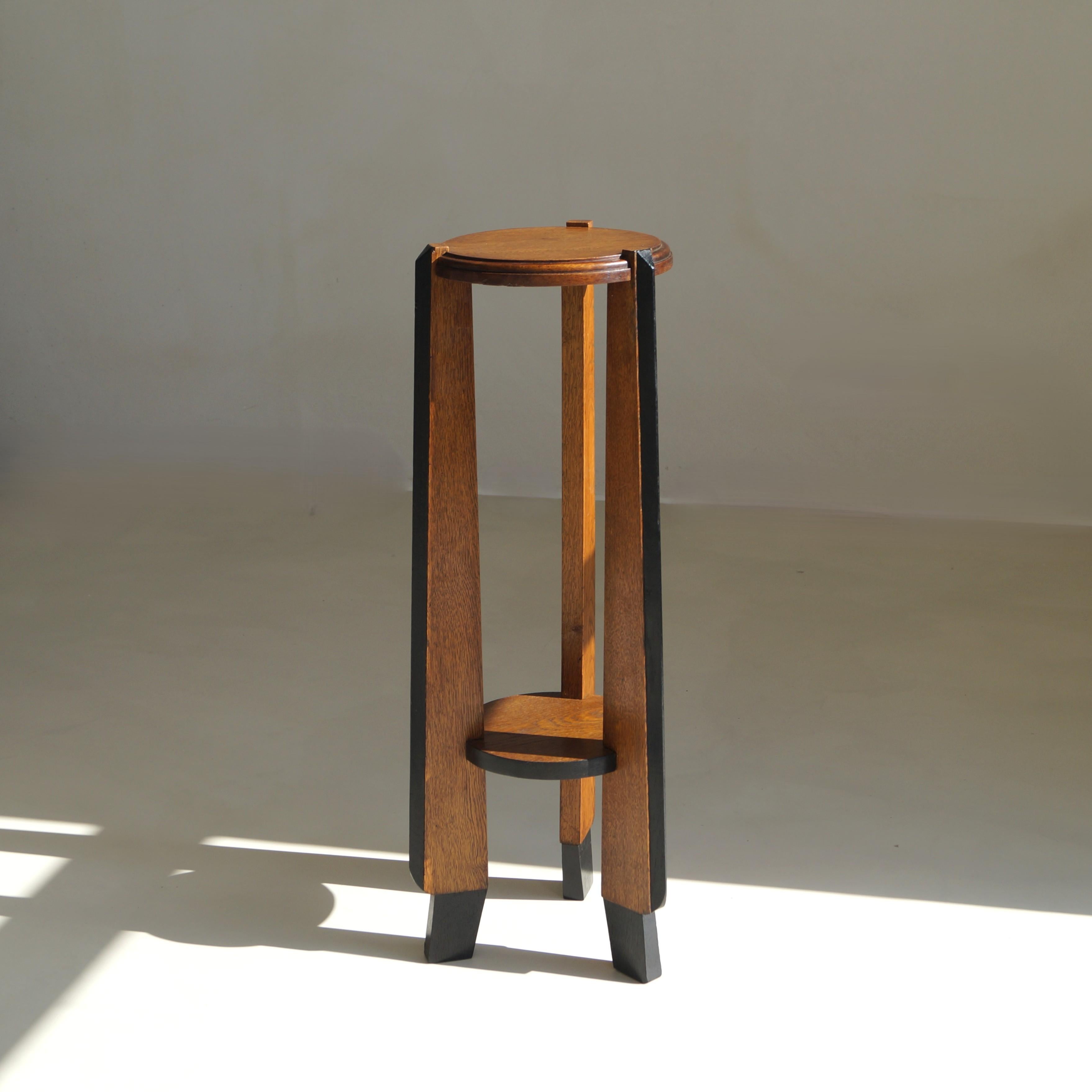 Un piédestal tripode distinctif et sculptural de l'école d'Amsterdam datant des années 1920, présentant un design rare et remarquable. Fabriquée en chêne avec des côtés teintés en noir, la pièce présente des caractéristiques modernistes évidentes